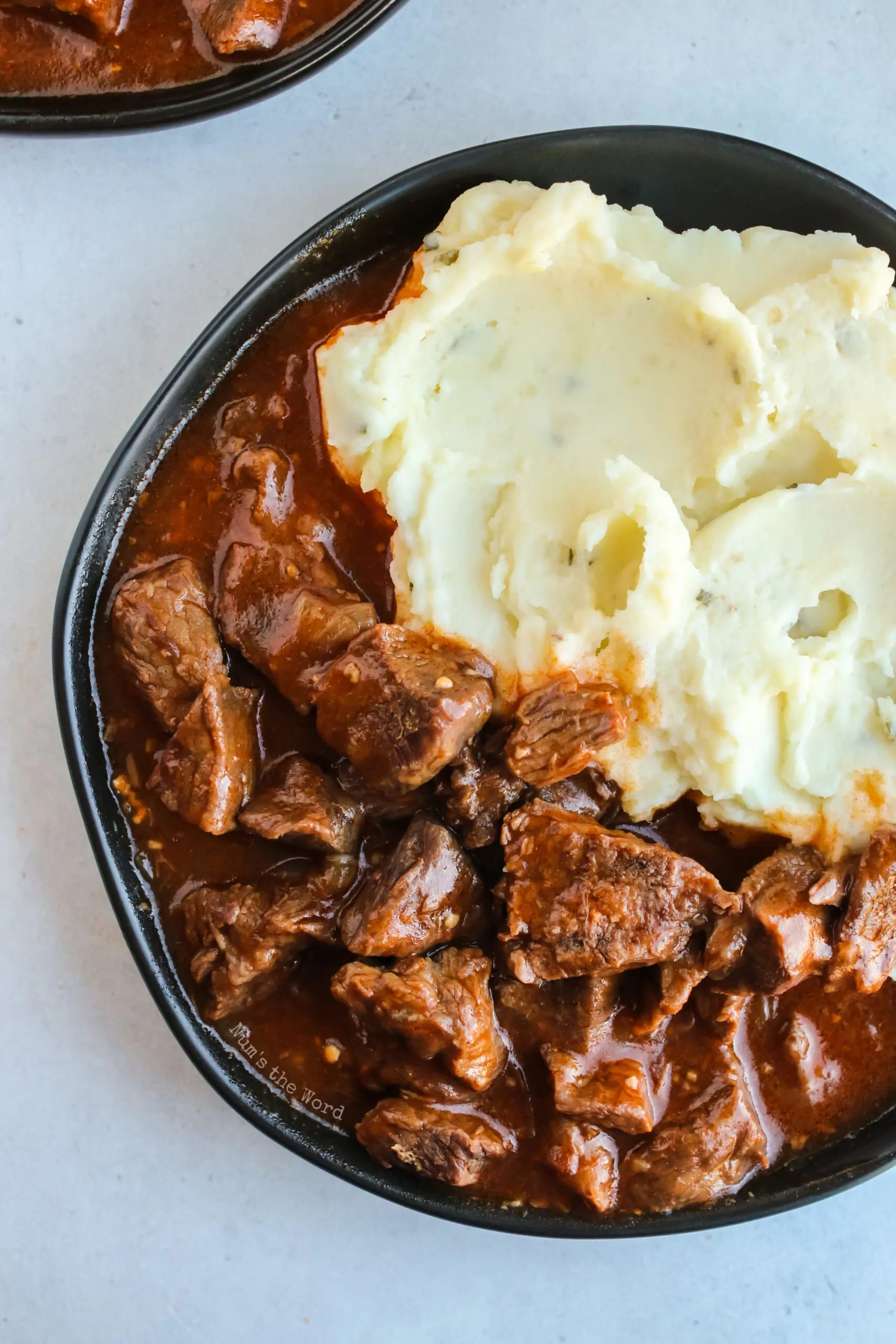 Top view of mashed potatoes and beef paprikash on a plate