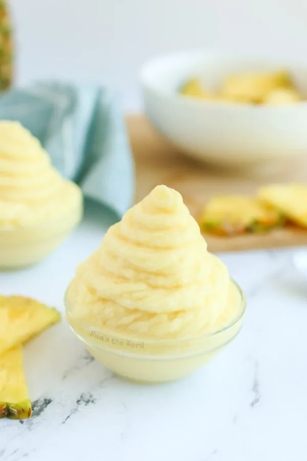 zoomed out image of two dole whips in cups ready to eat.