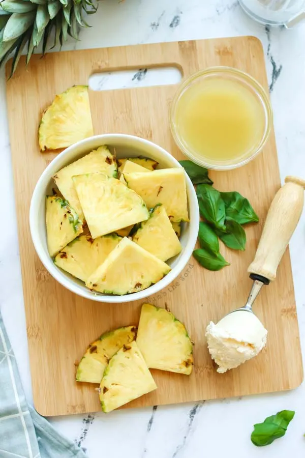 All ingredients laid out on a cutting board. Pineapple, pineapple juice and ice cream