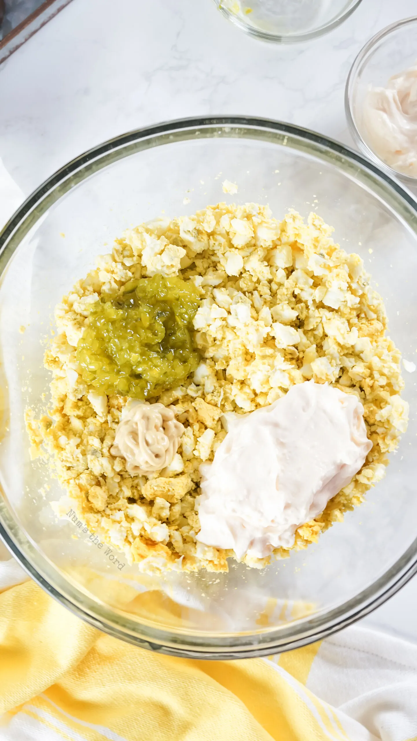 diced hard boiled eggs, mayonnaise, pickle relish and Dijon mustard in a bowl, unmixed.