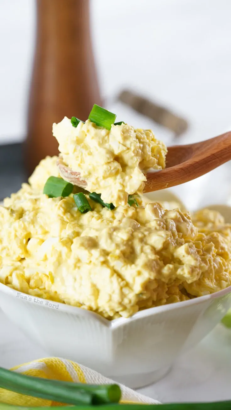 egg salad in a bowl with a spoon scooping some out