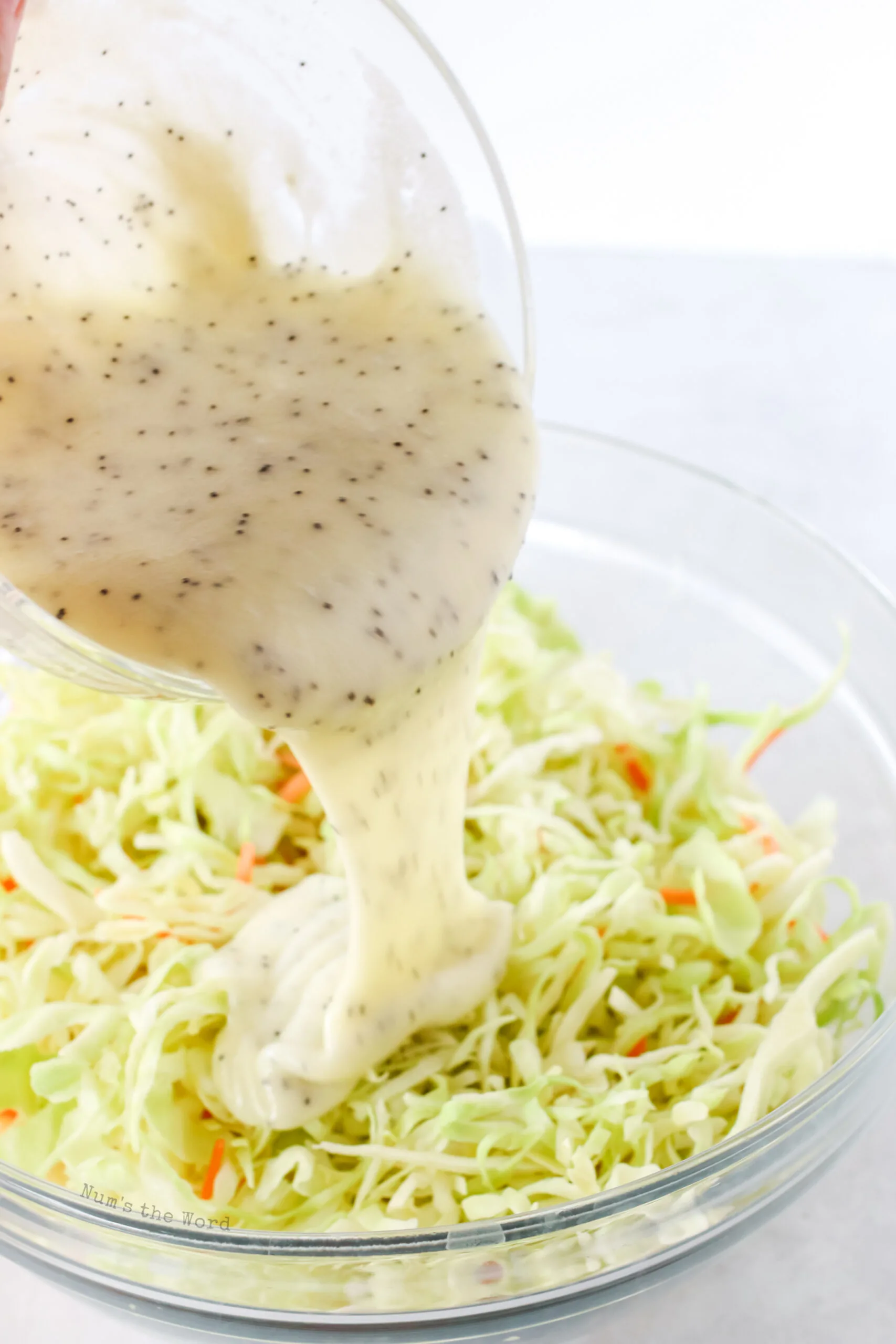 coleslaw dressing being poured over coleslaw.