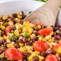 zoomed in image of grilled corn salad with wooden spoon.