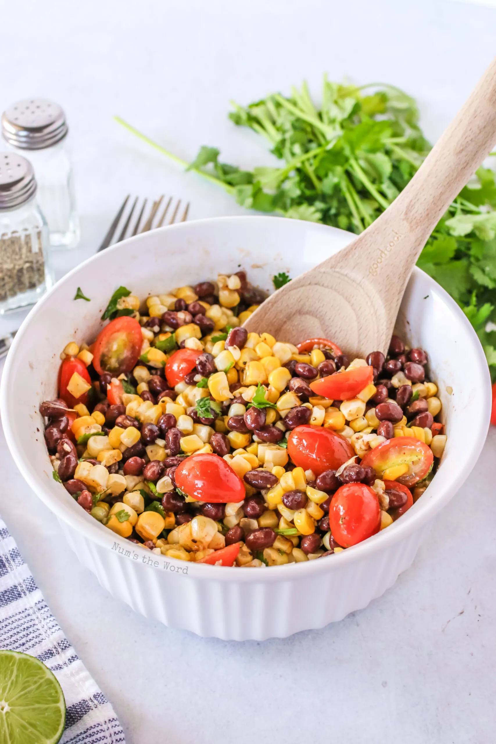 grilled corn salad in a bowl. zoomed out image with wooden spoon.