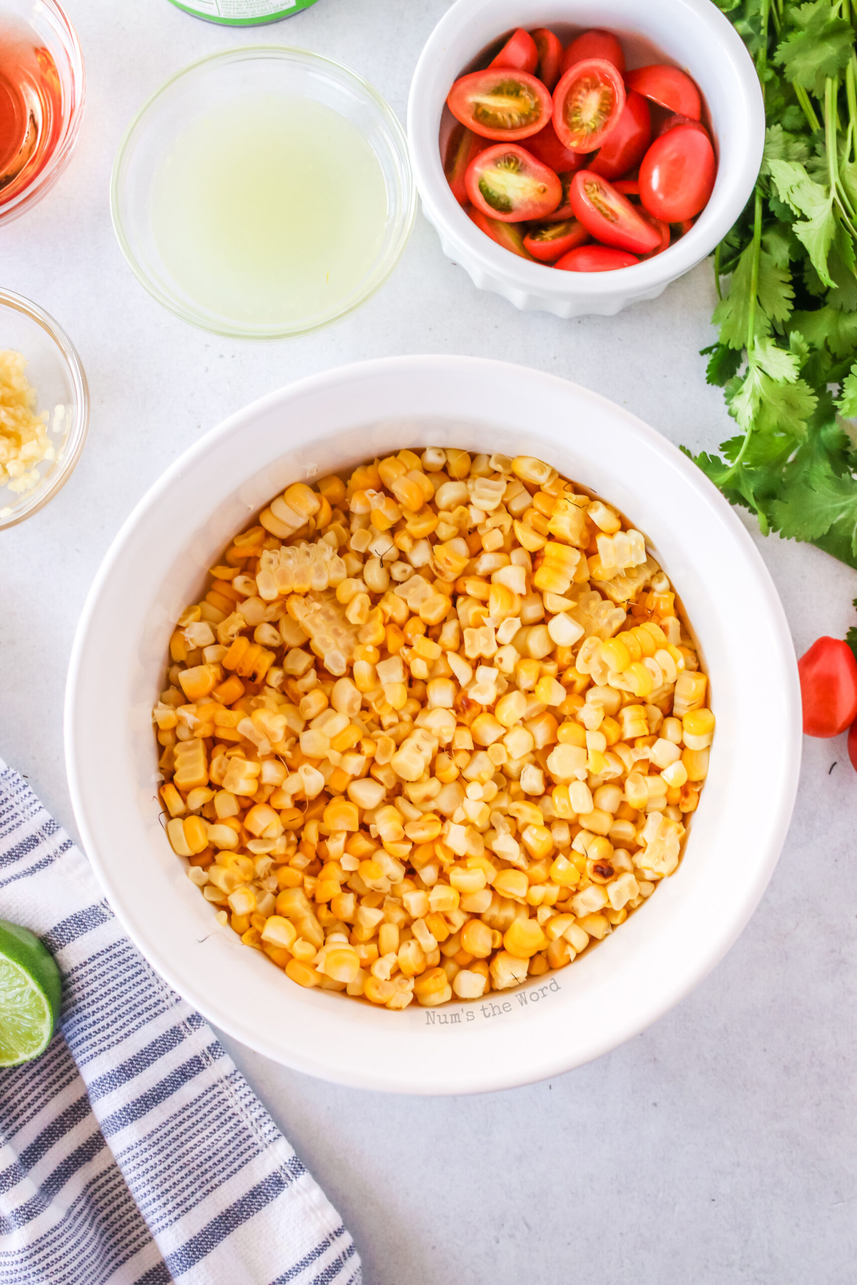 corn kernals are stripped off corn cobs and into a bowl.