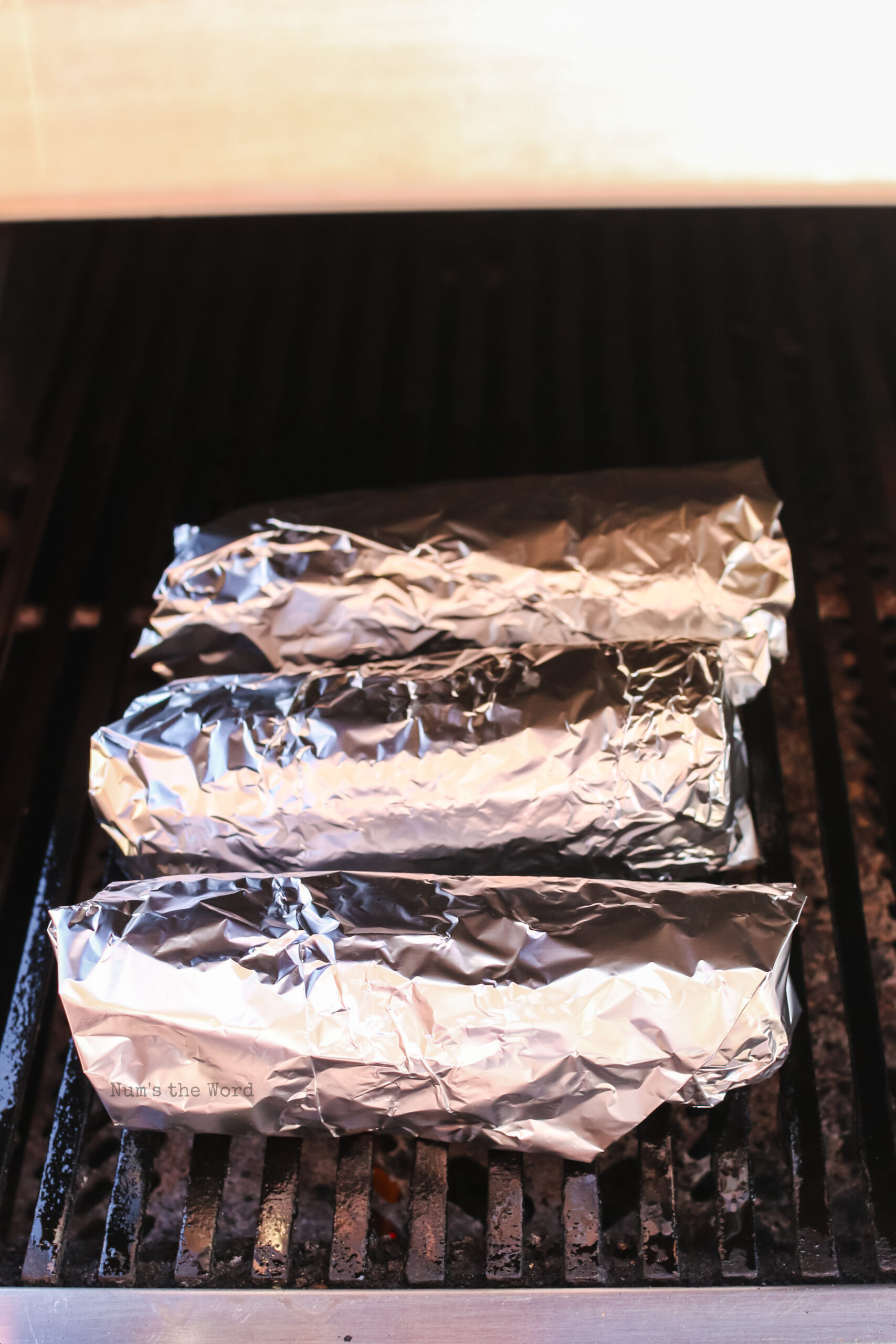 3 corn cobs wrapped in foil on grill