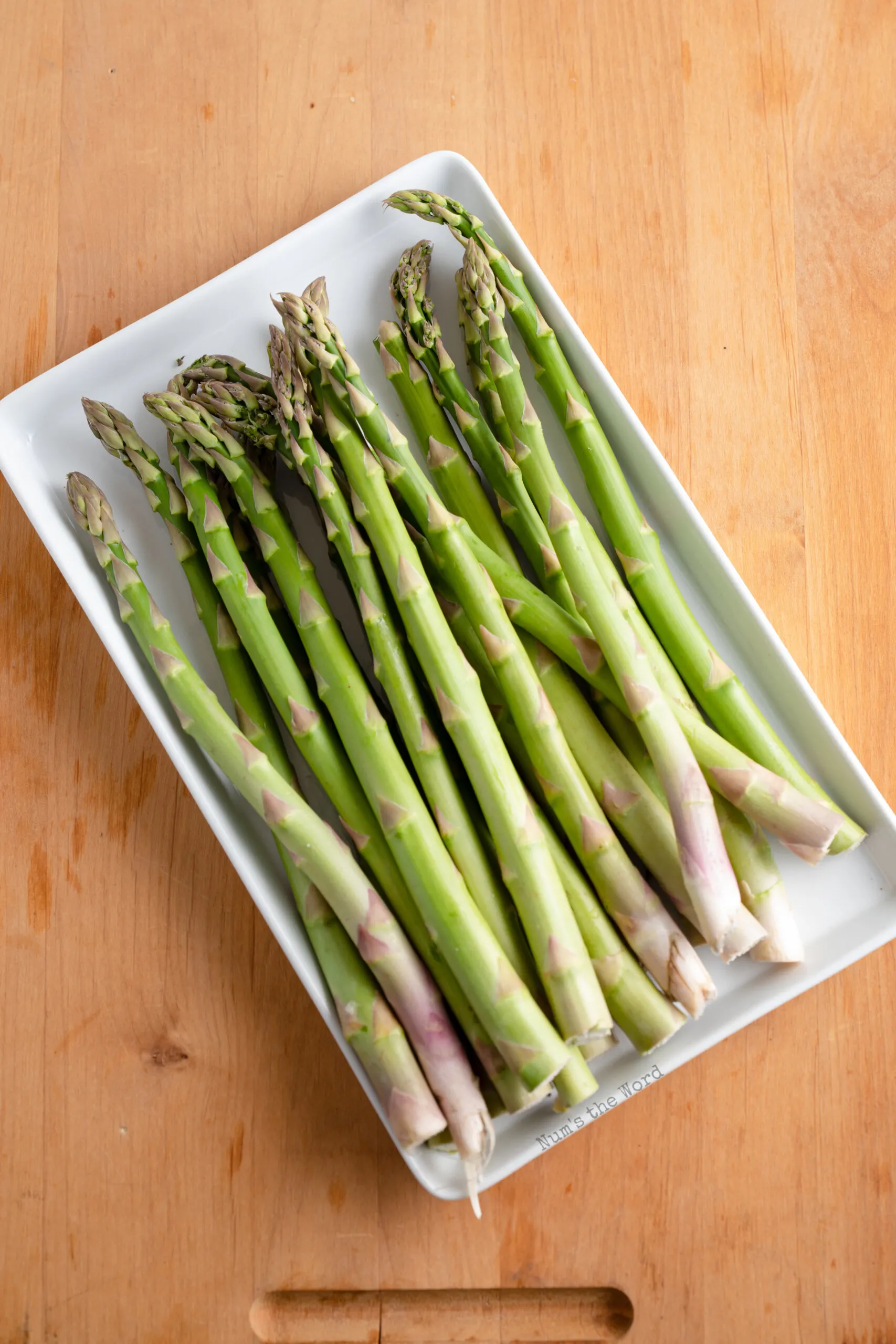 fresh asparagus on a plate, ready to be prepped and cooked.