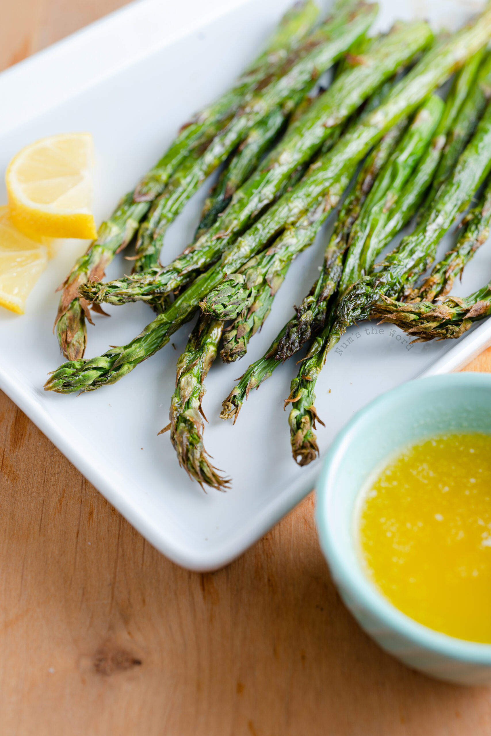 asparagus tips facing camera with bowl of garlic dipping sauce.