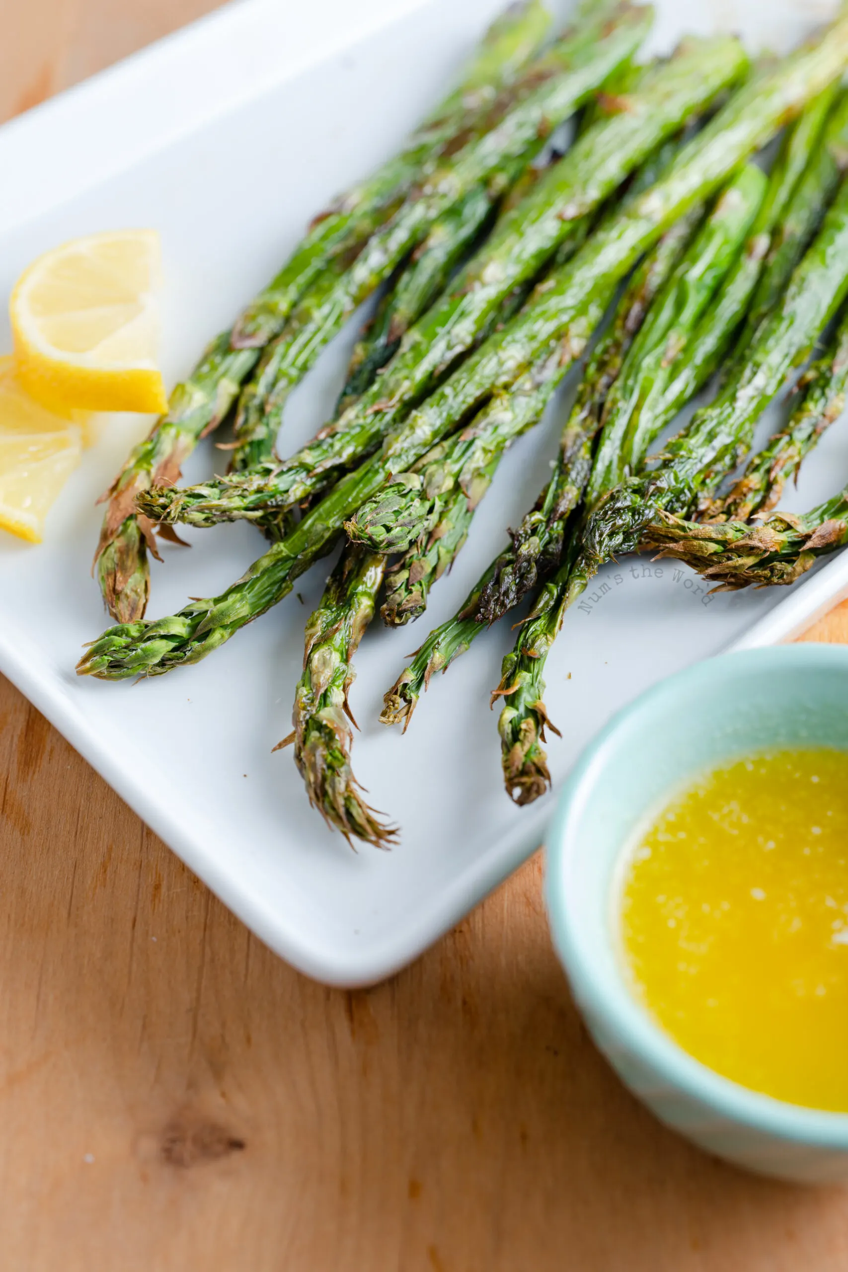 asparagus tips facing camera with bowl of garlic dipping sauce.