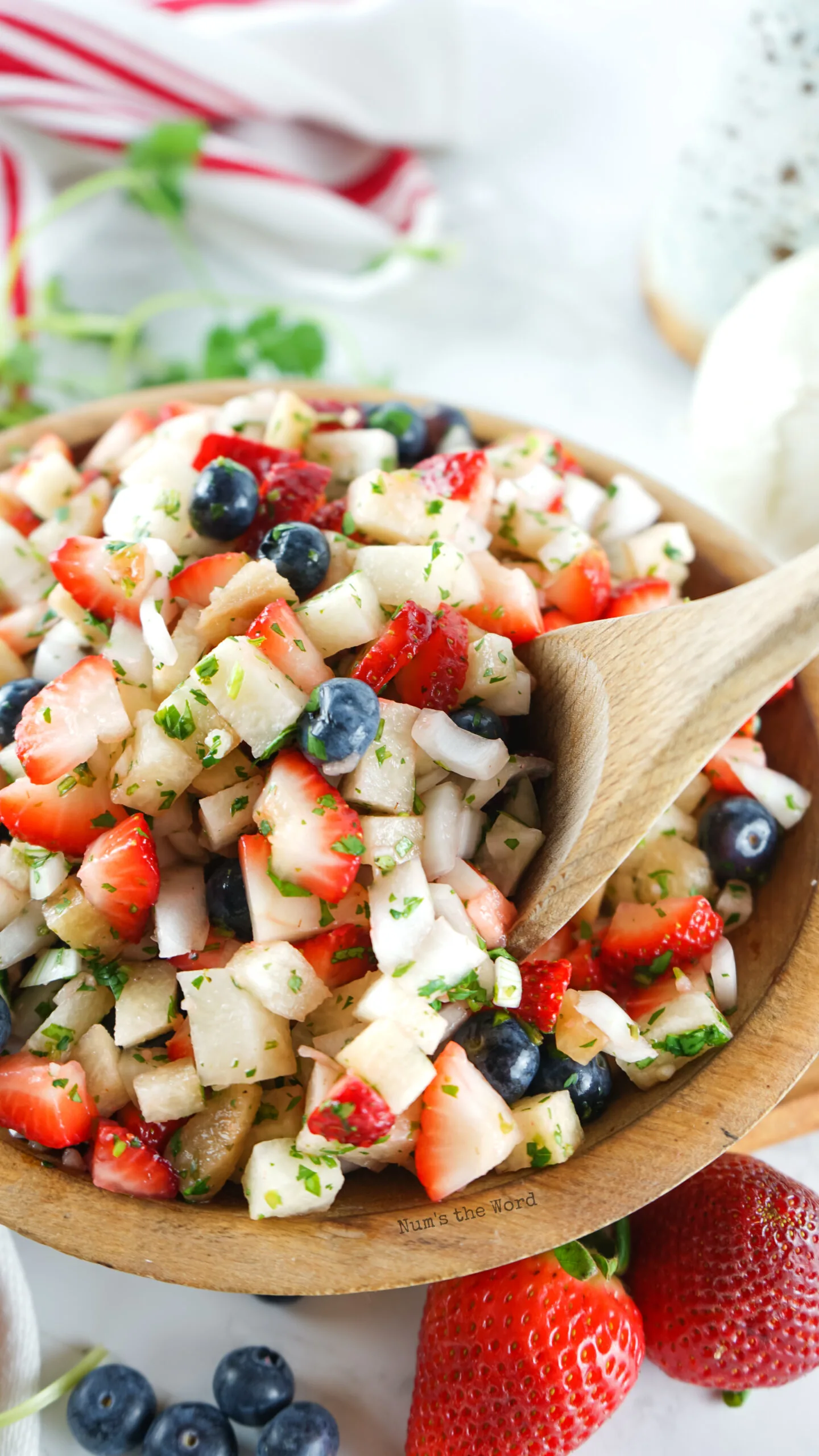 fruit salsa in a bowl with a wooden spoon in the bowl.