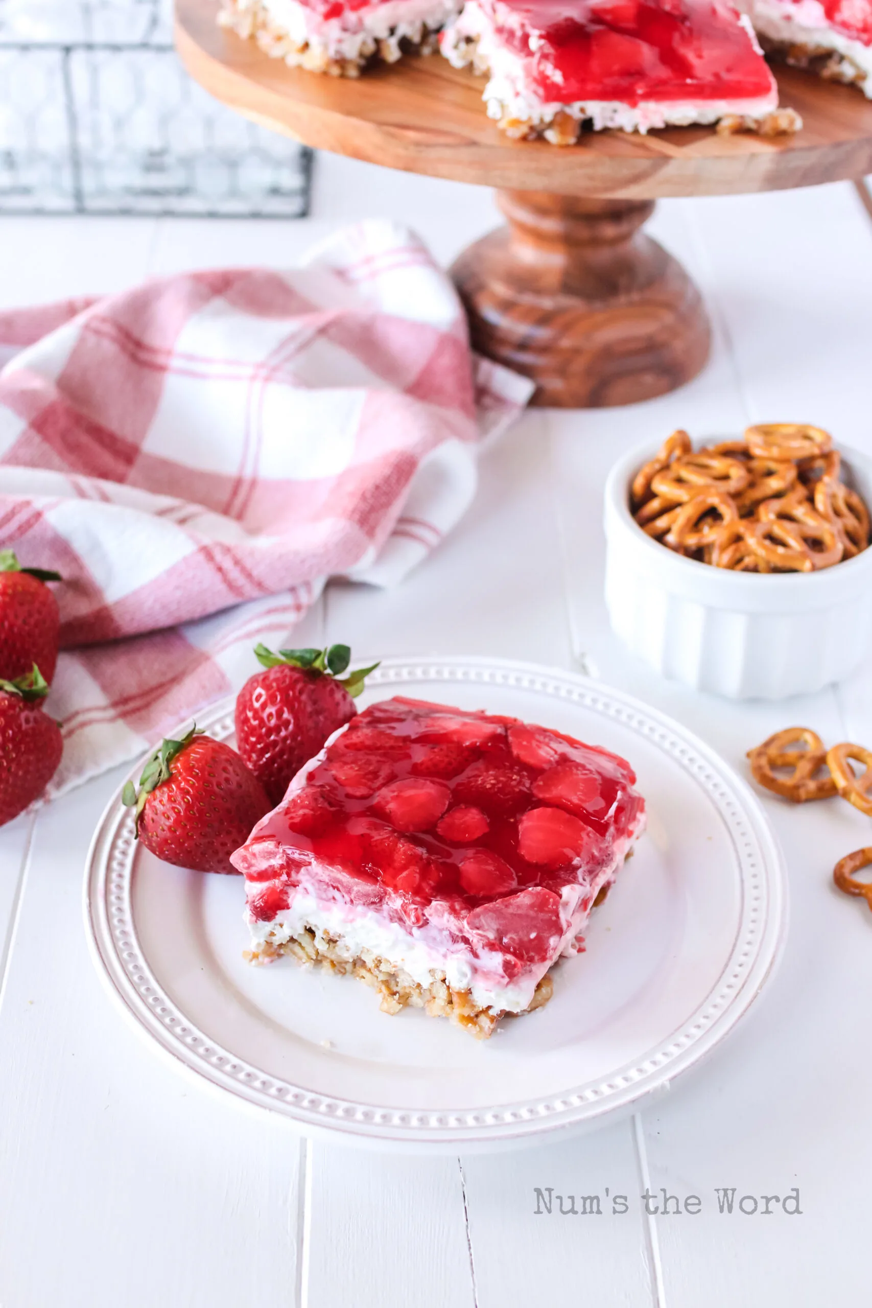 zoomed out image of a slice of strawberry pretzel salad on a plate.