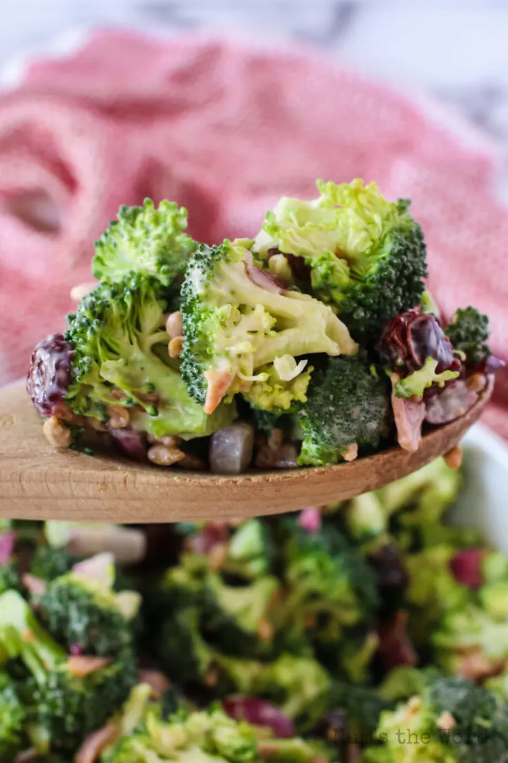 wooden spoon scooping a portion of broccoli salad out of the bowl
