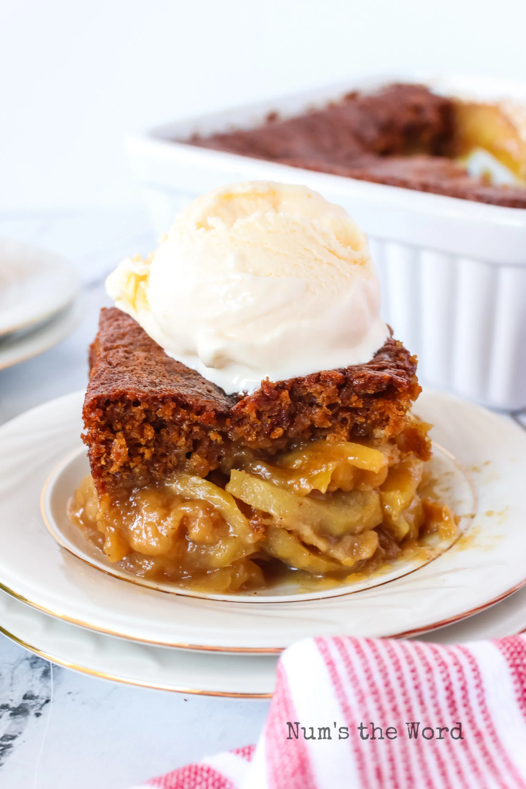 slice of cake on a plate with apples under and a scoop of ice cream on top.