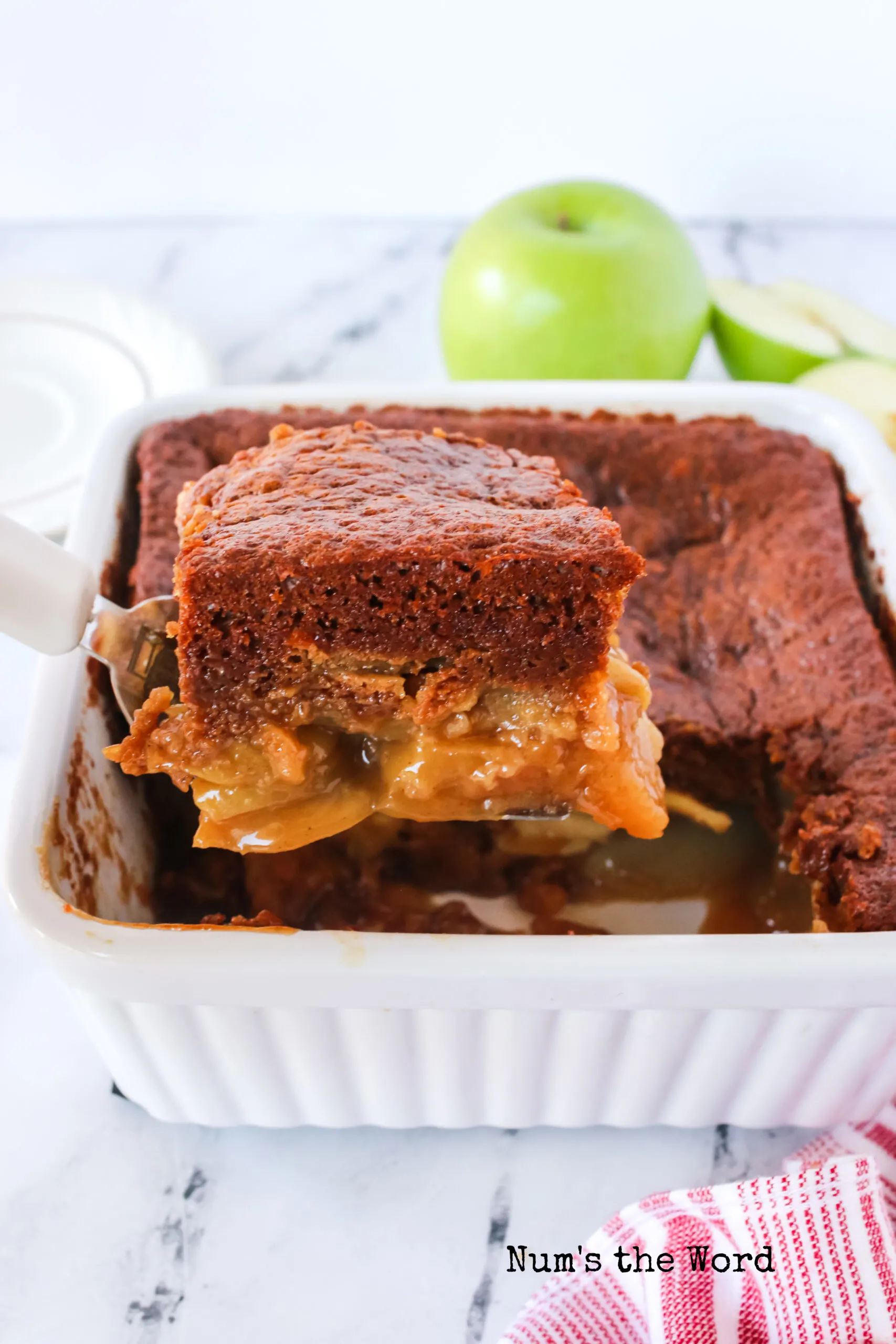 side image of apple gingerbread cake with a slice being removed from pan.