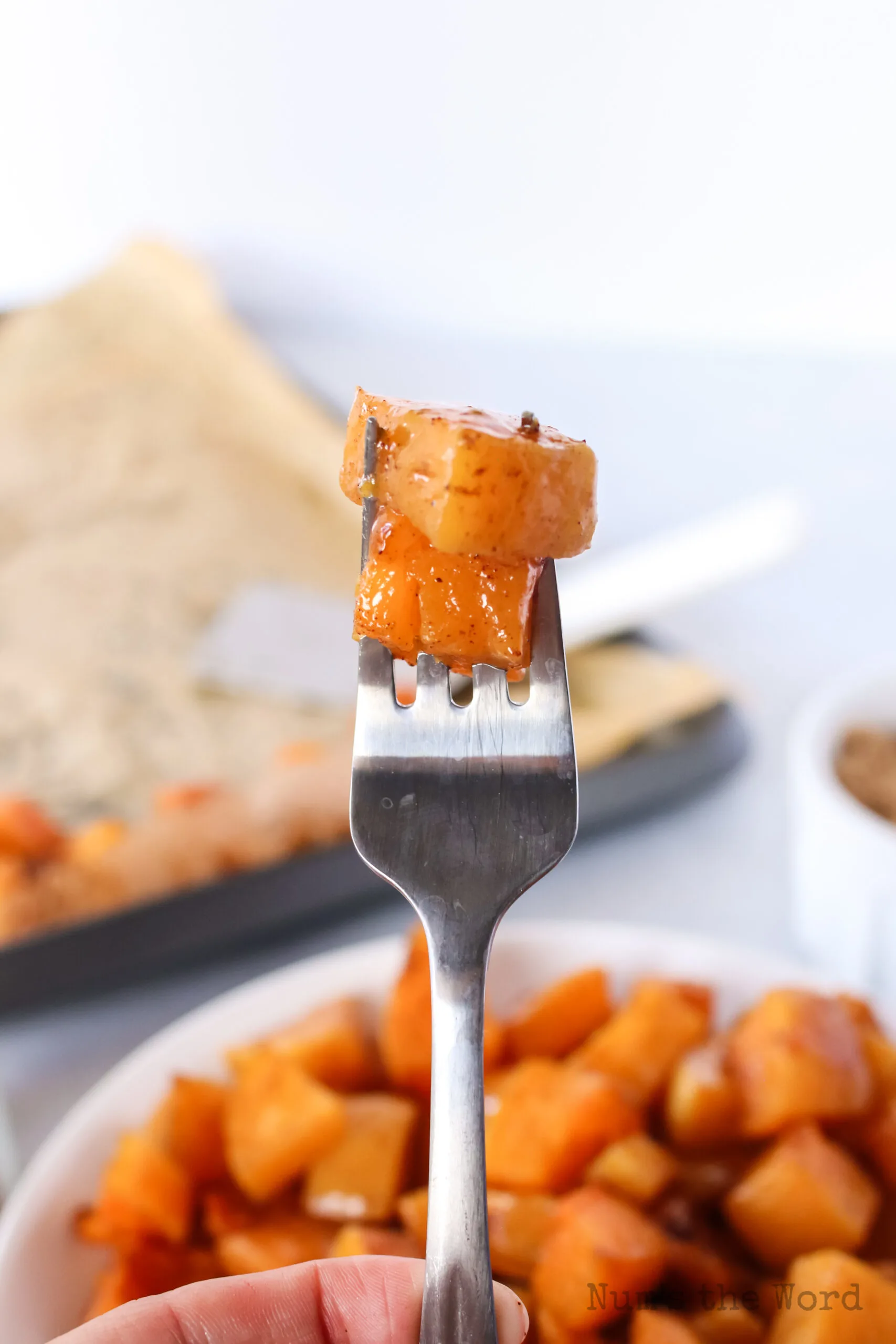 hand holding up a fork with 2 pieces of cut squash on it