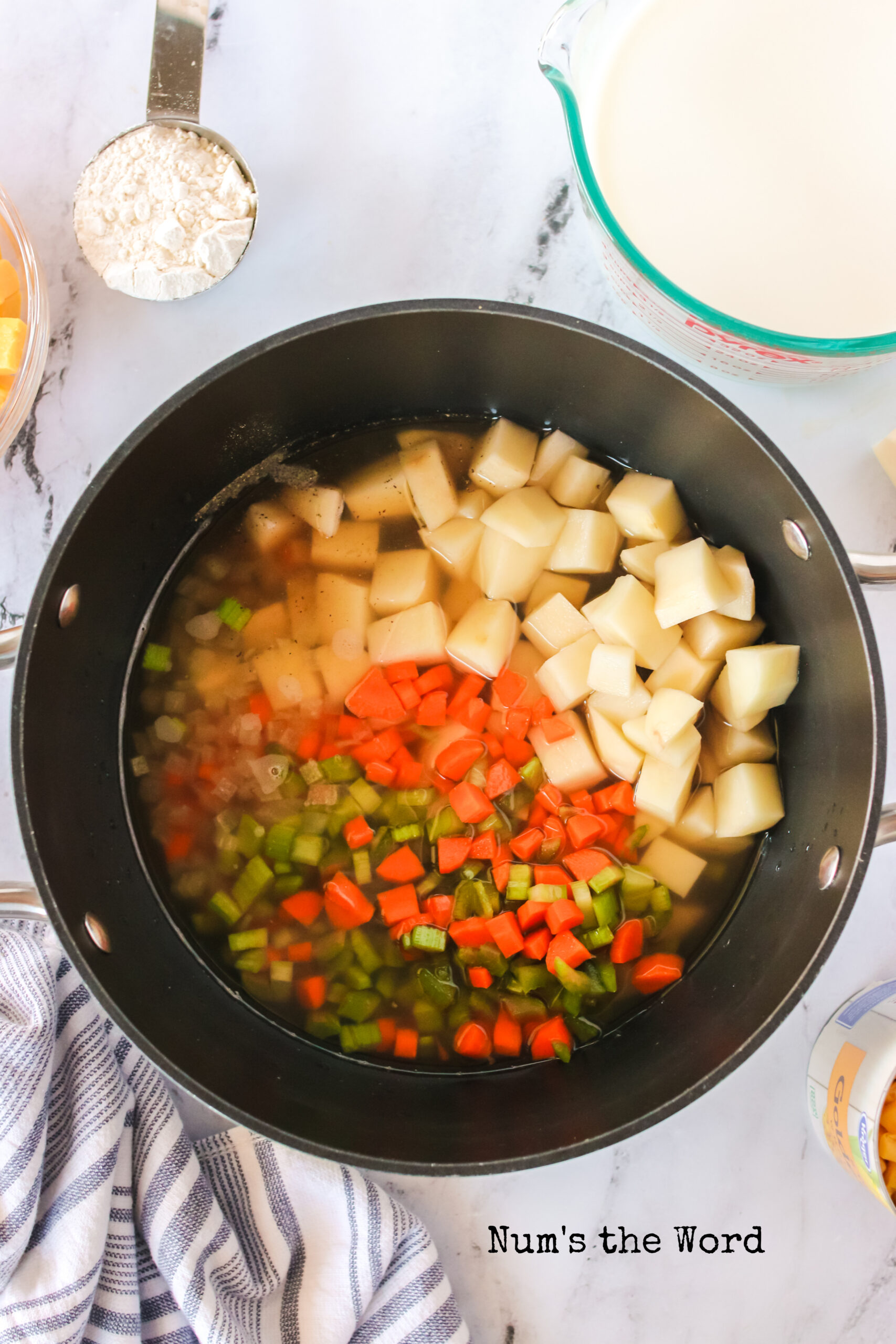 chicken broth, potatoes, carrots, celery, onion and black pepper added to a pot.