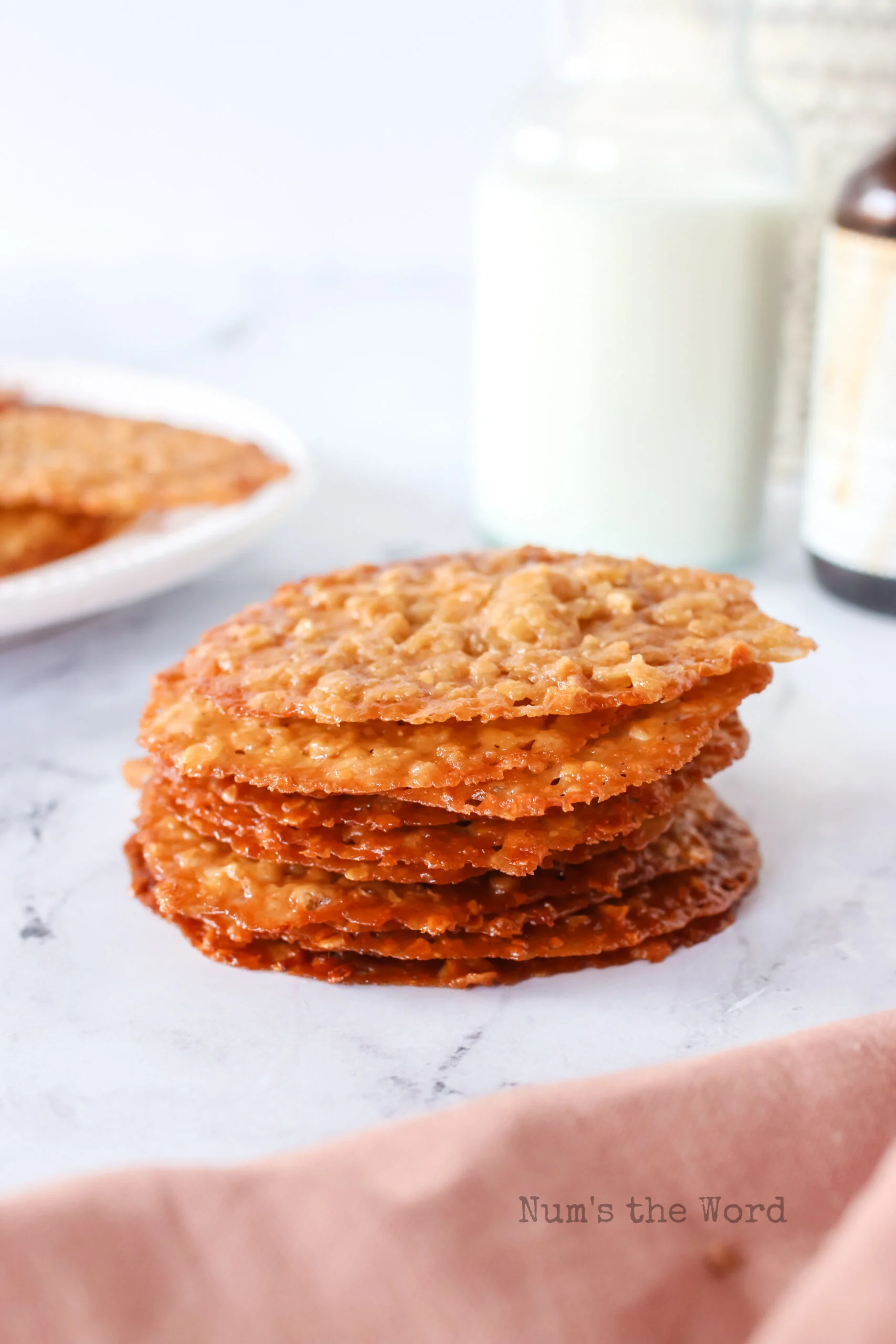 baked cookies stacked up with a glass of milk behind.