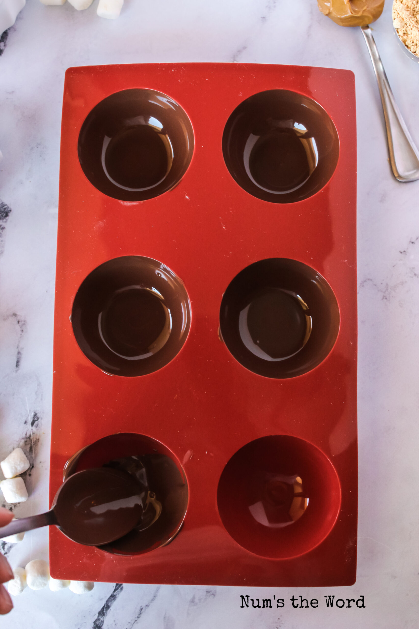 melted chocolate spread inside a silicone chocolate mold.