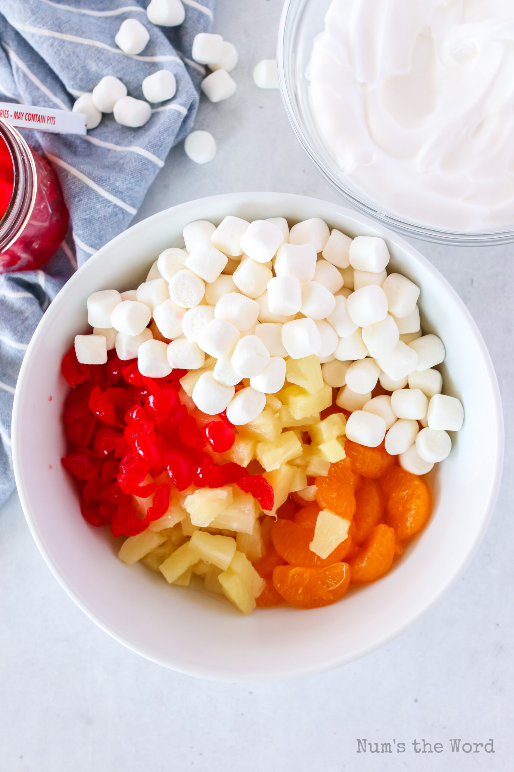 orange, pineapple, cherries and marshmallows in a bowl