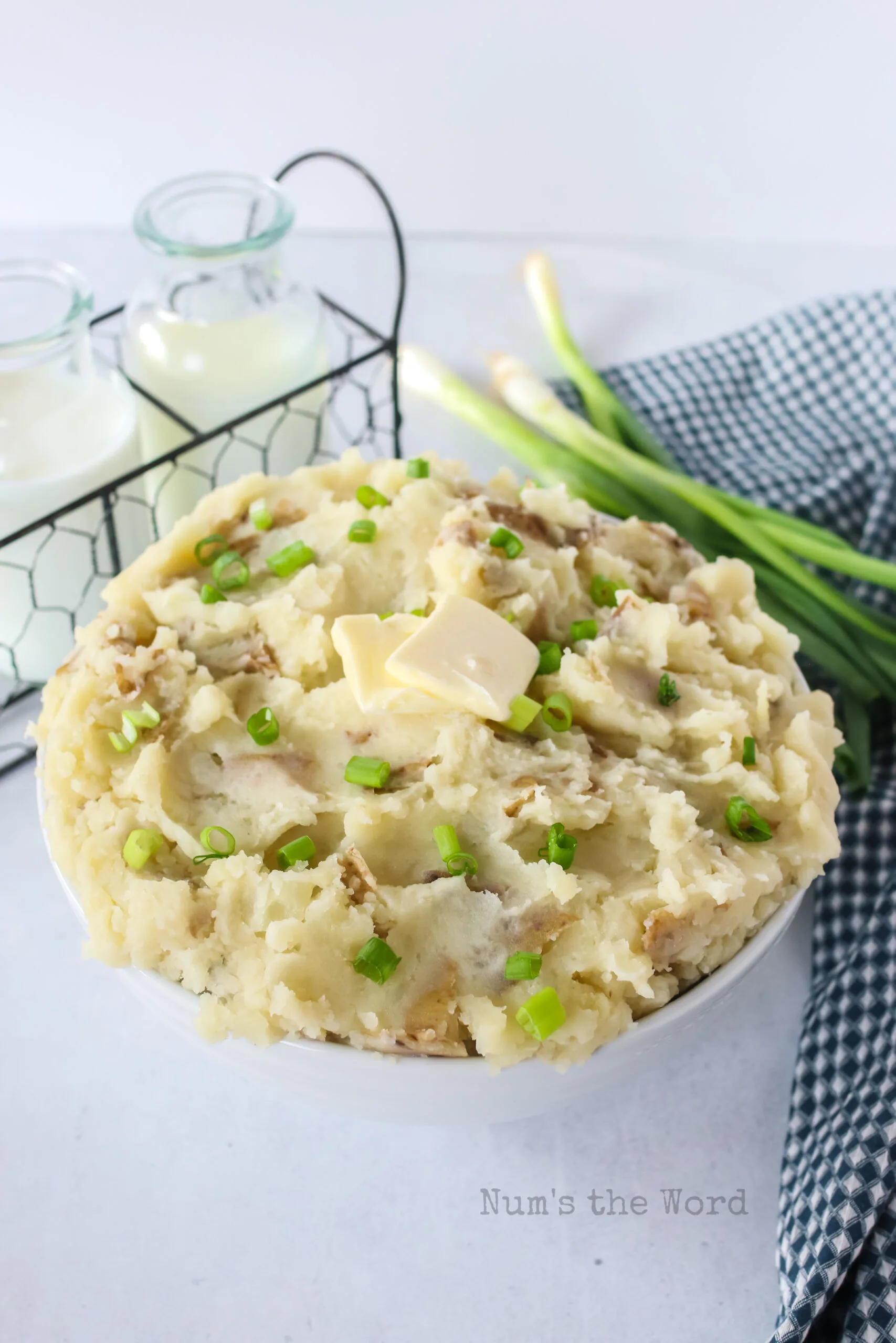 zoomed out side view of potatoes in a serving bowl with green onions on top.