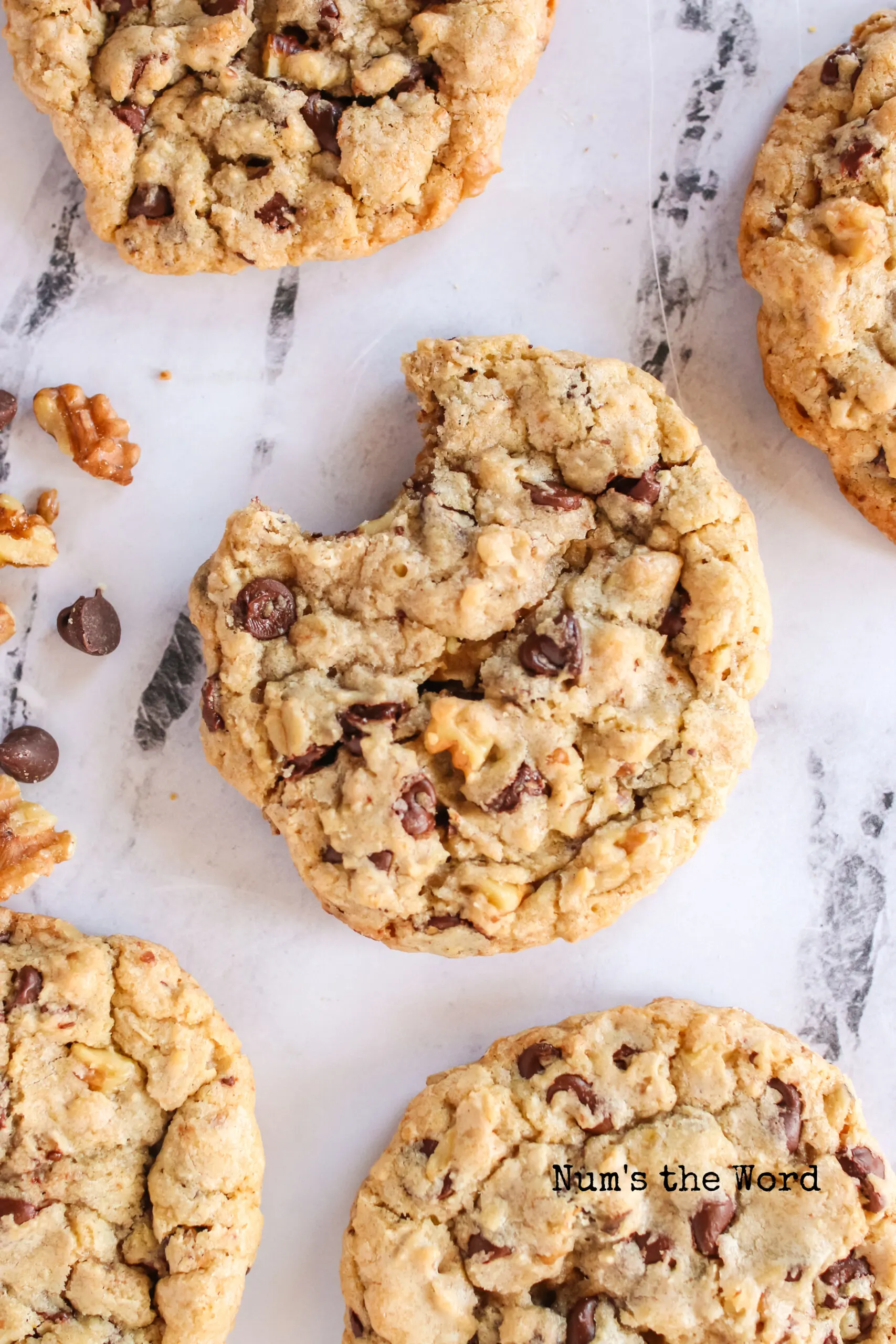 chocolate chip cookies laid out on counter. Main cookie has a bite taken out.