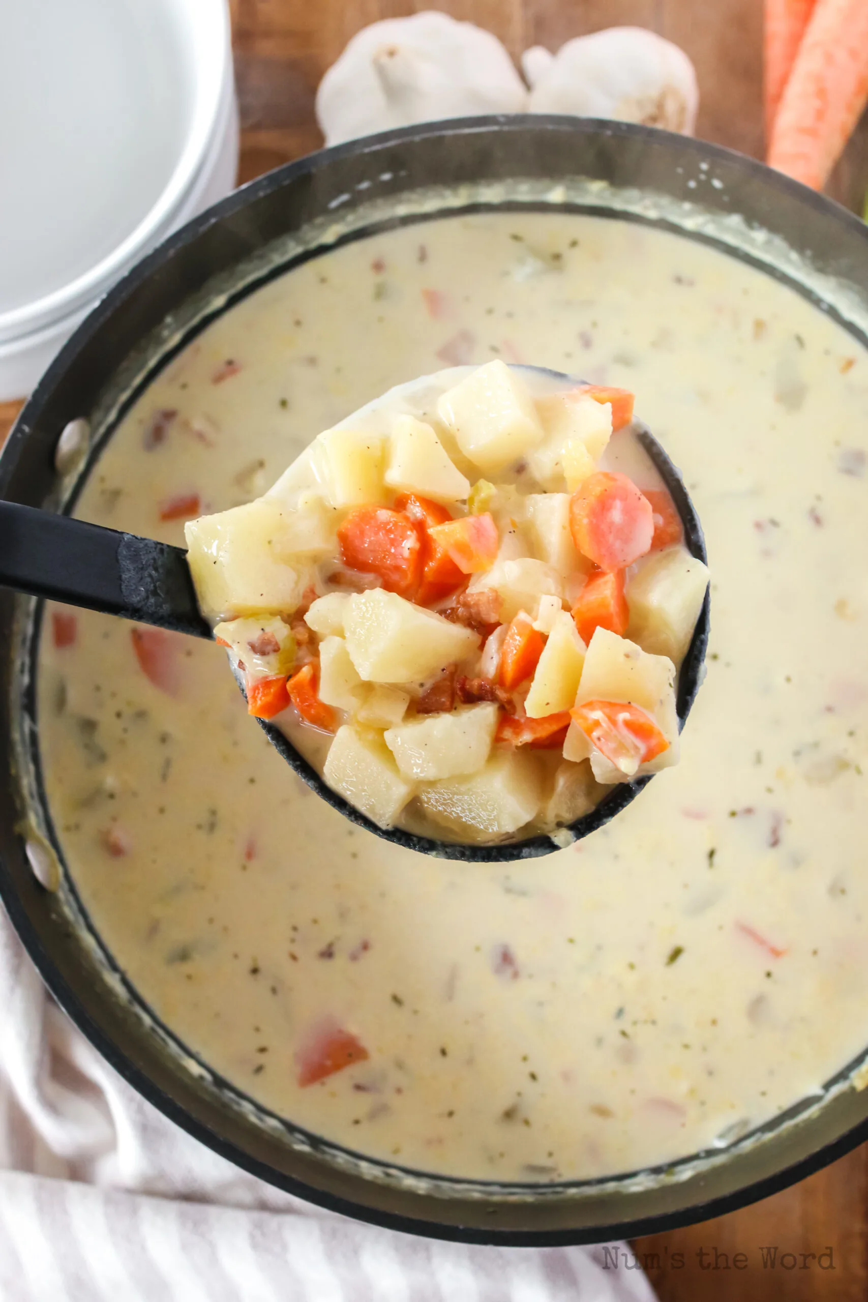 Cooked soup in a pot with a ladle full being held above.