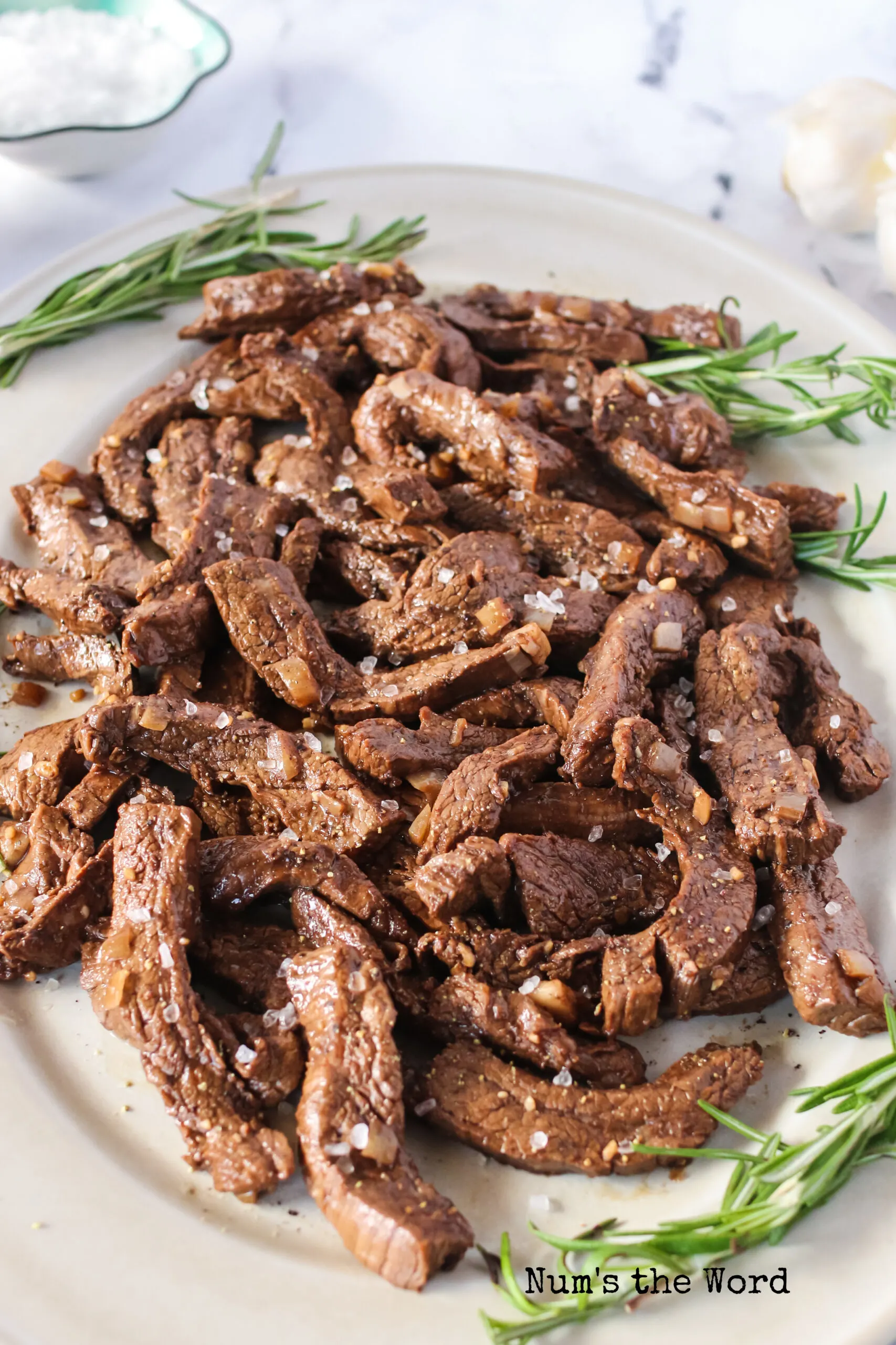 zoomed out image of cooked flank steak ready to serve on a platter.