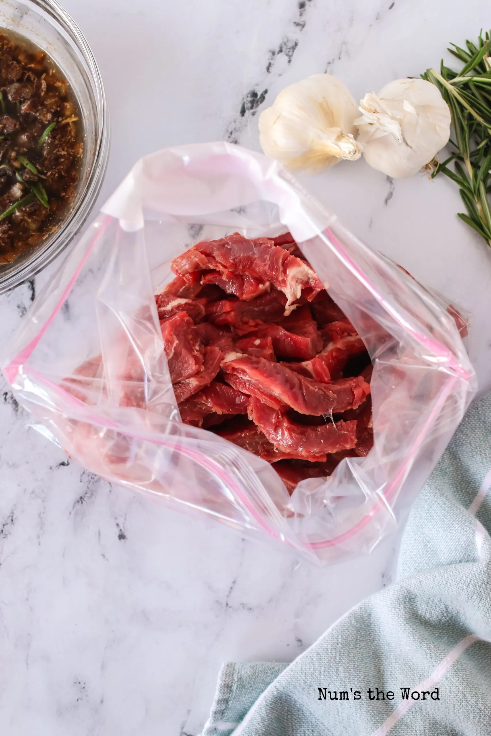 Sliced flank steak in a bag, ready for marinade to be poured on top.