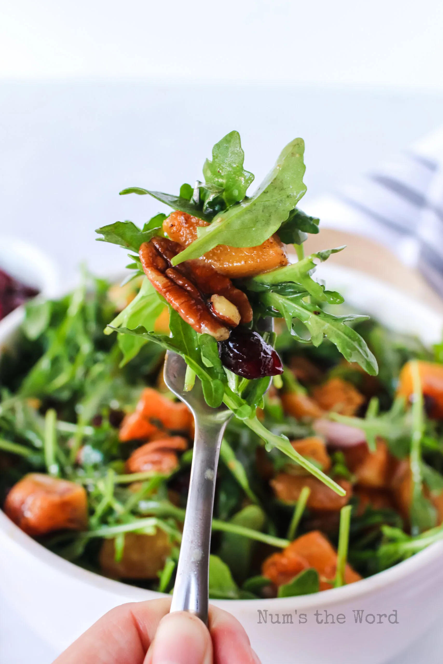 fork holding up a portion of salad, ready to eat.