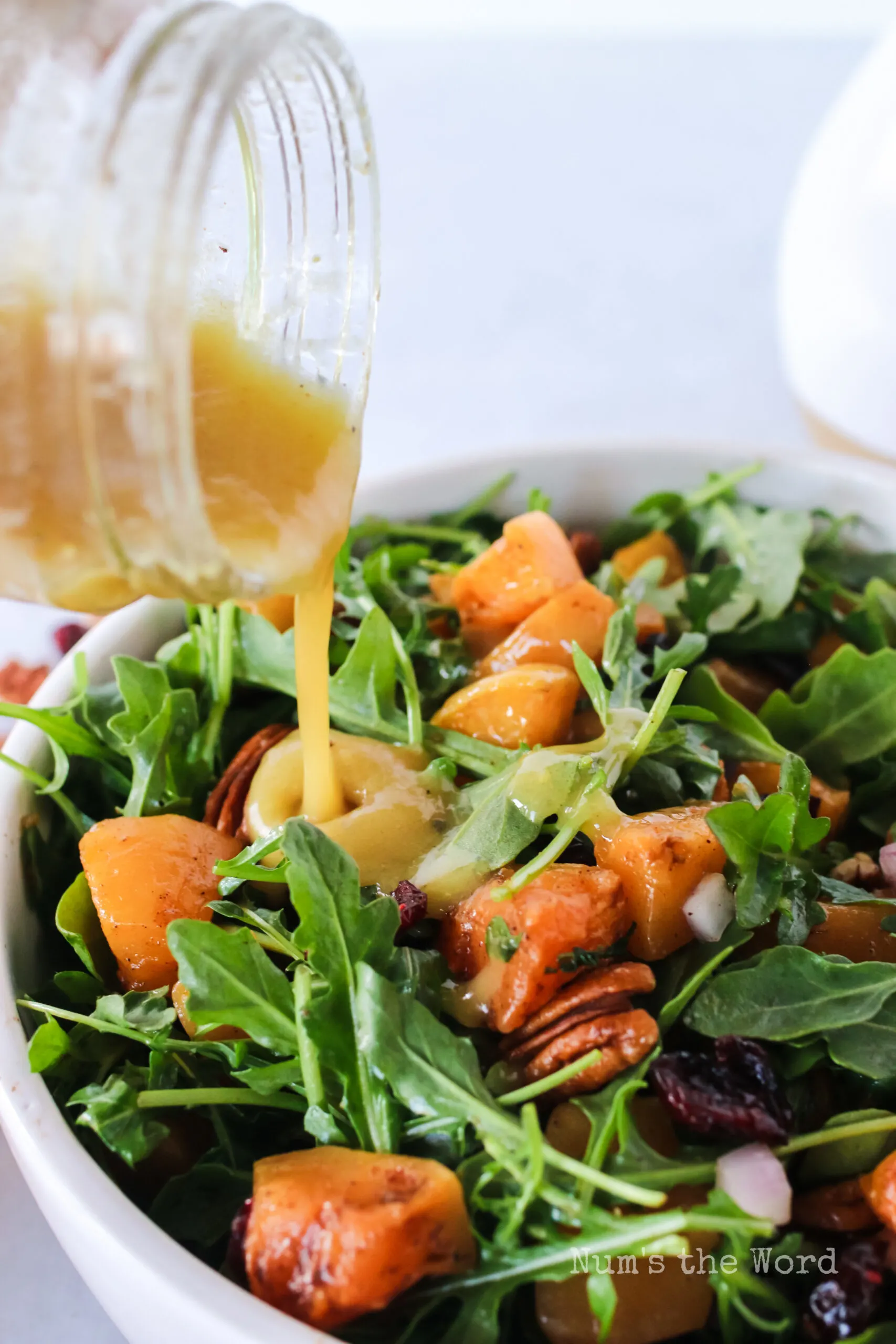 salad dressing being poured over salad