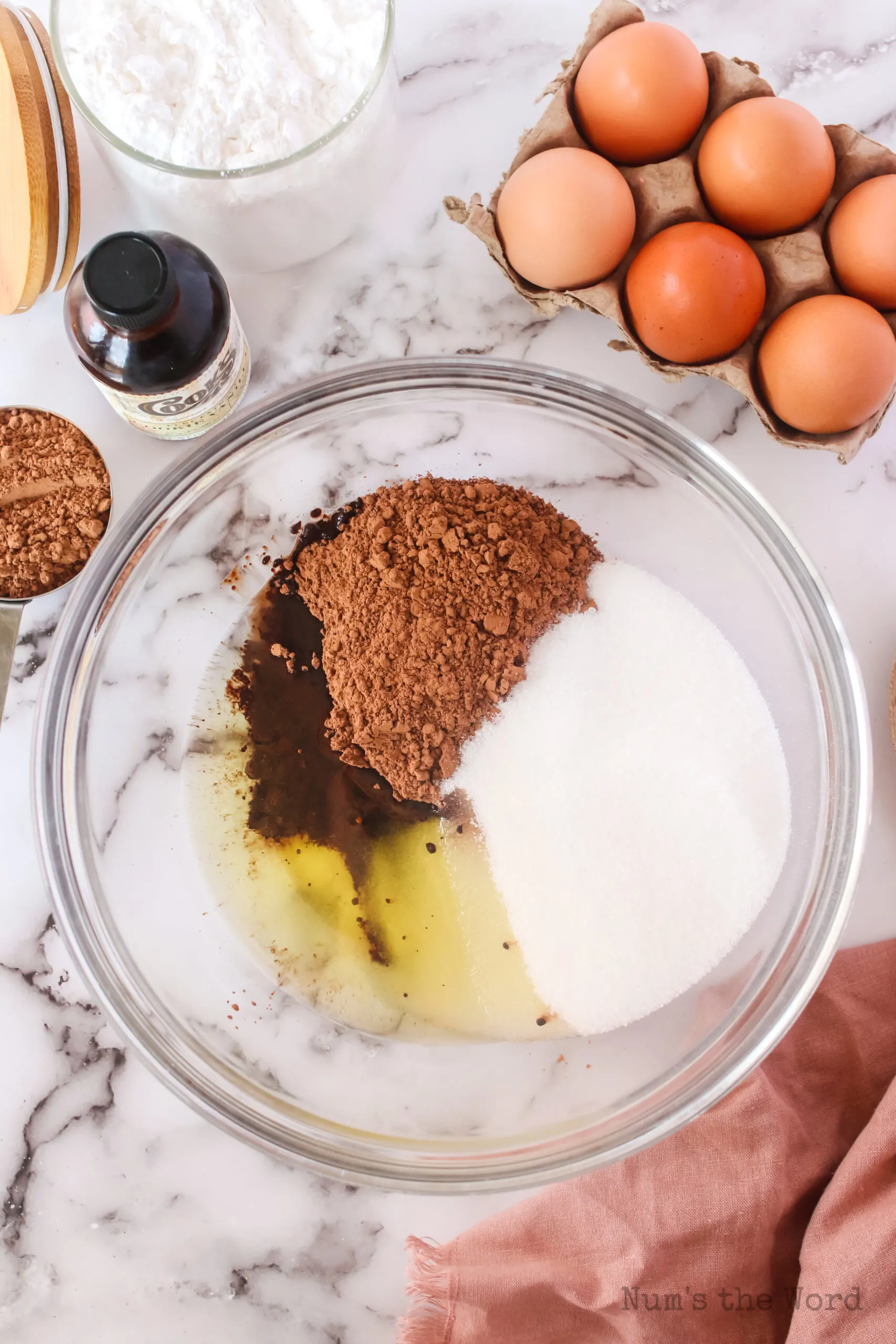 cocoa powder, white sugar and oil in a bowl, unmixed.