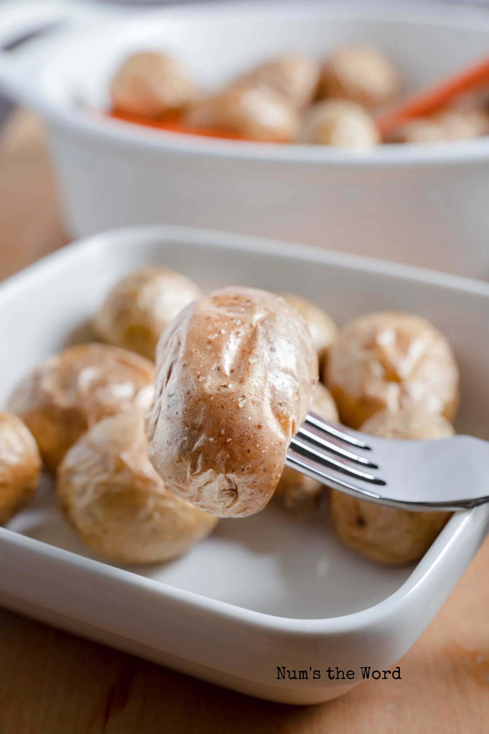 fork pricked into a baby potato and holding it above the plate.