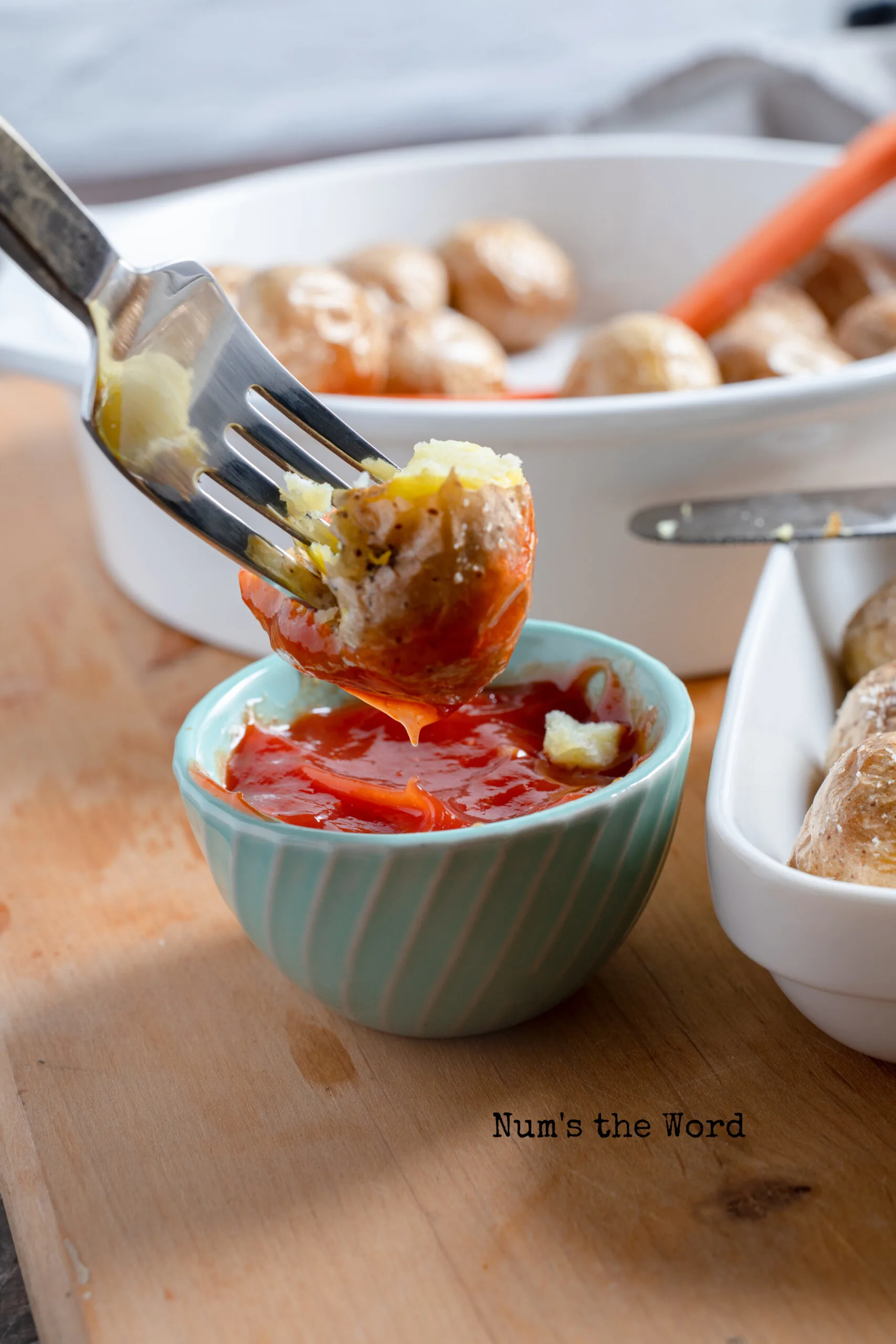 fork dipping half a baby potato into ketchup