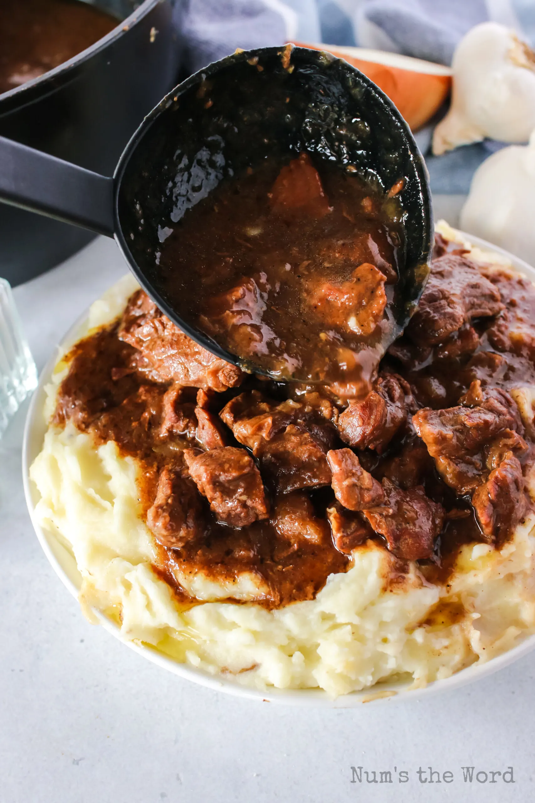 spoon scooping beef tips being poured over gravy.