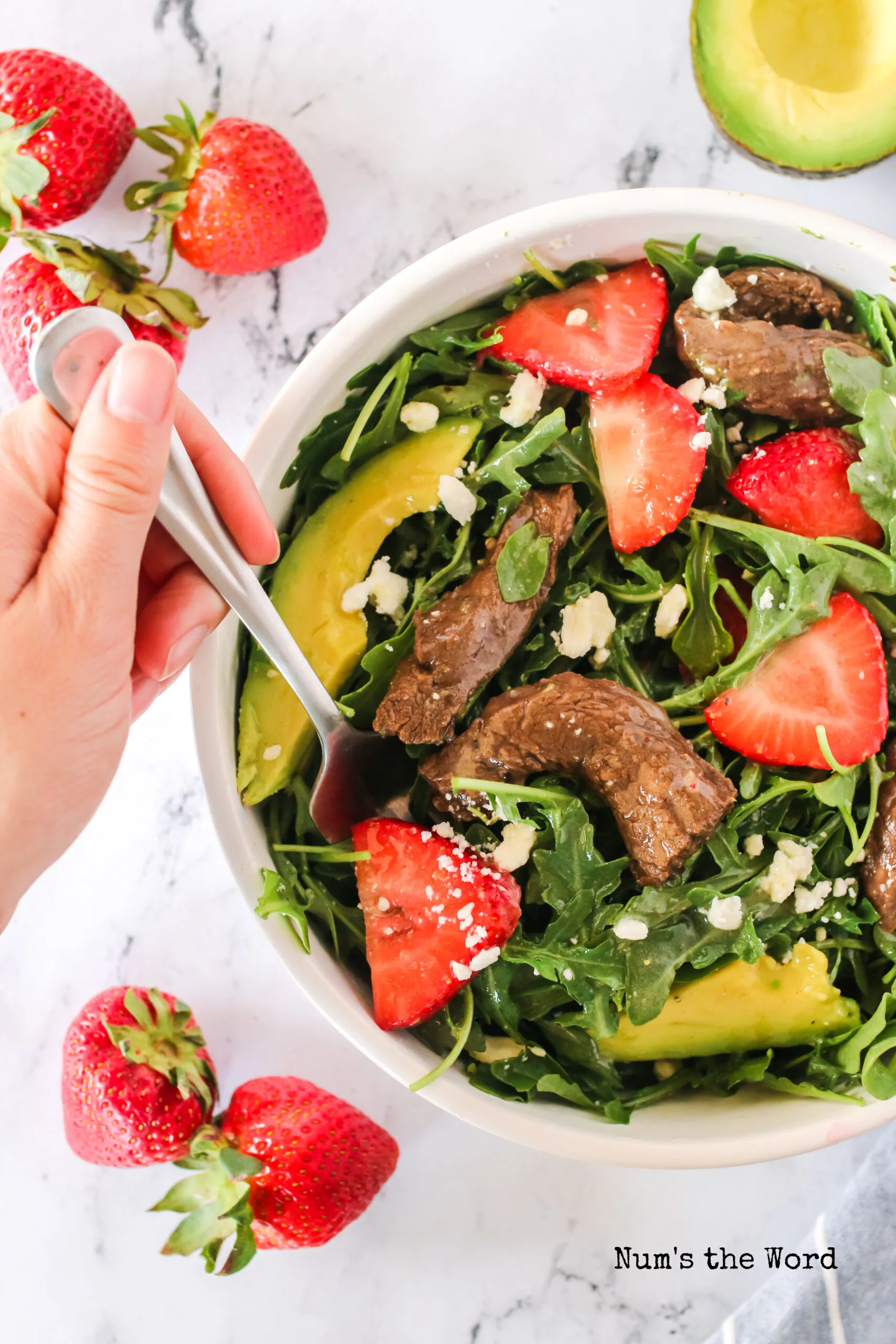 salad in a bowl with a hand and fork