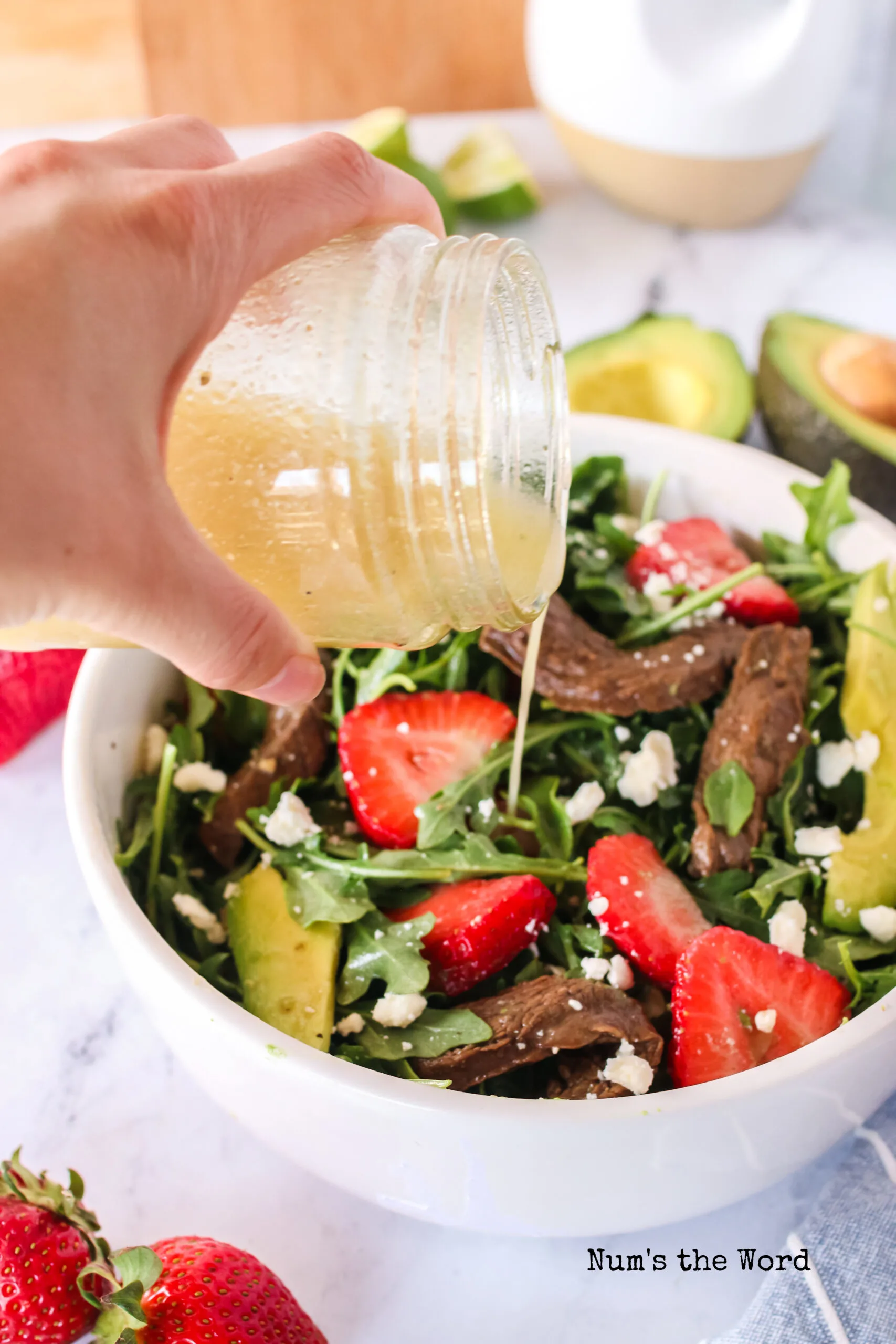 salad dressing being poured over the salad.