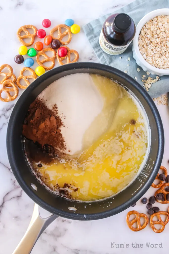 melted butter, sugar, cocoa powder, and milk all added to a pot, unmixed.