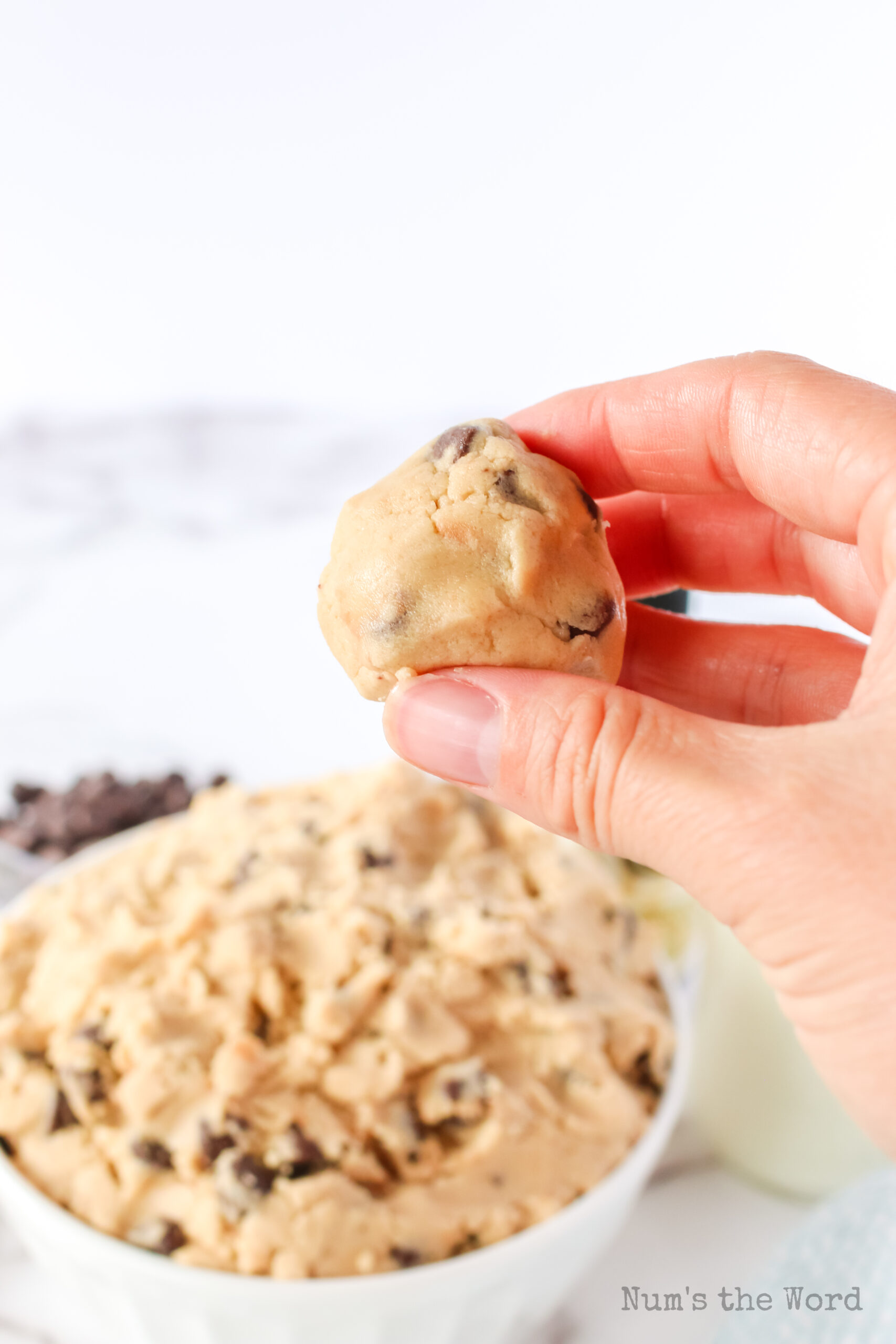 hand holding cookie dough ball, ready to eat.