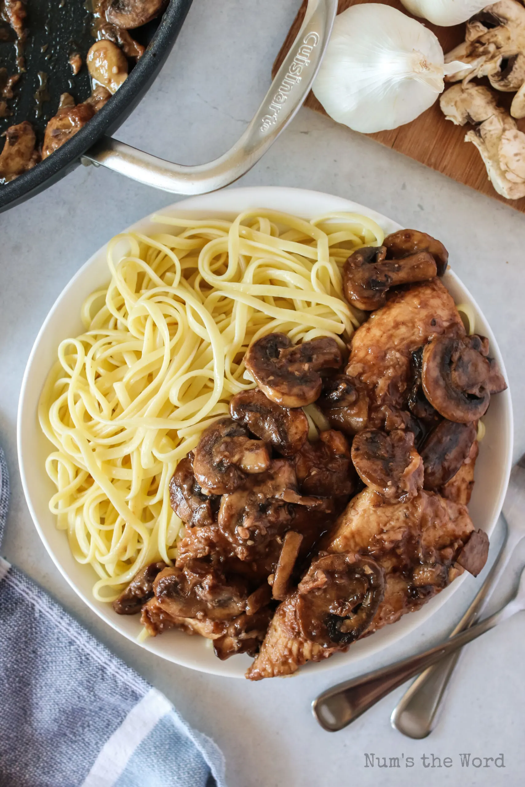 zoomed out image of chicken marsala on plate with pasta