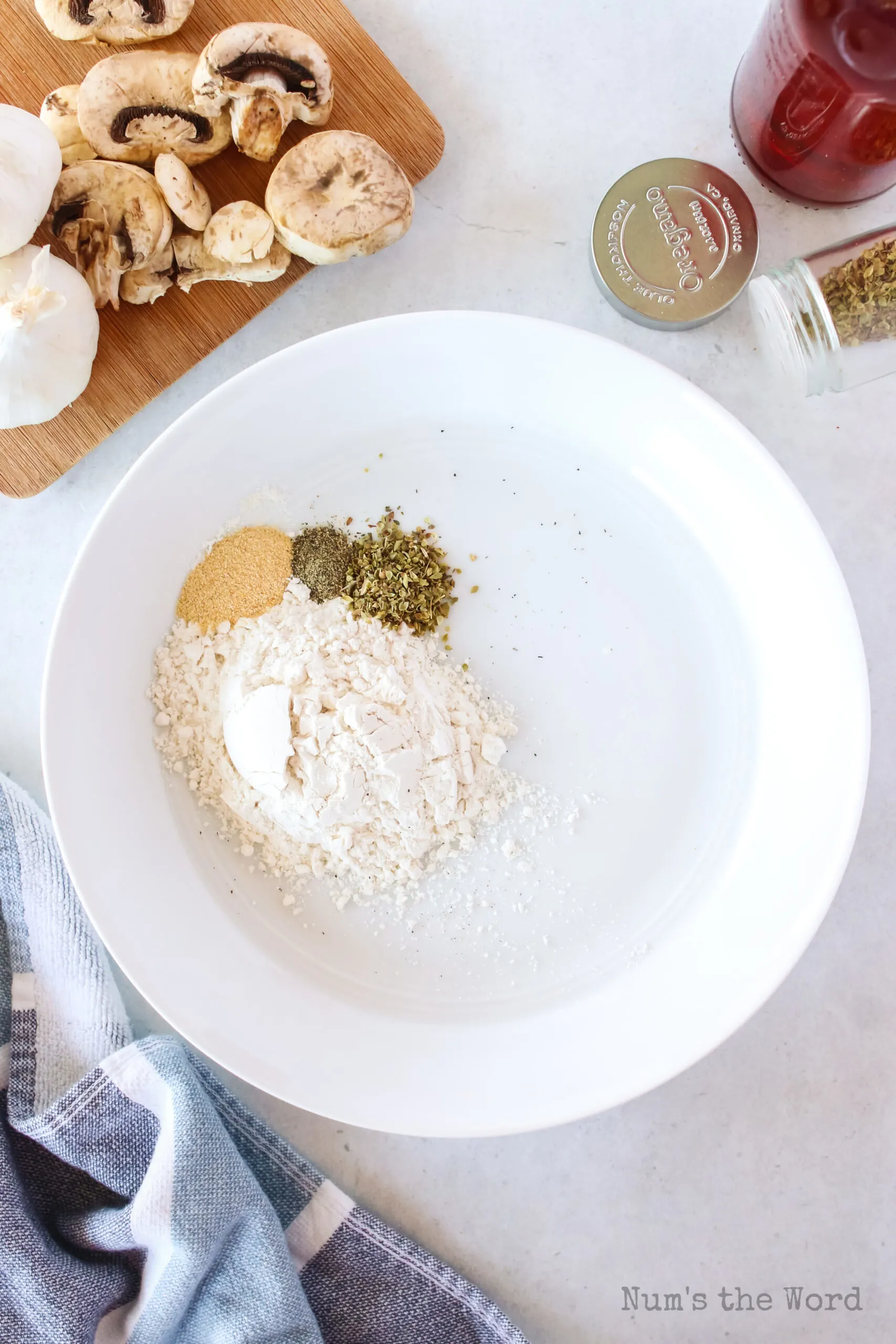 flour, garlic salt, pepper ad oregano in a bowl about to be mixed.