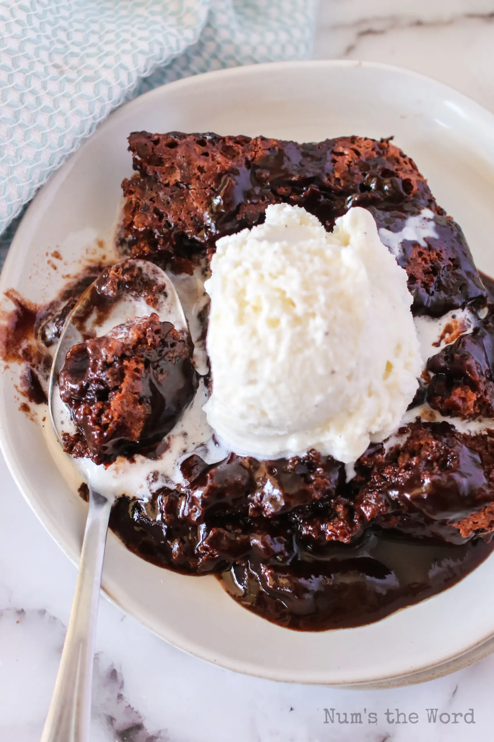 a Spoon on the plate with a scoop of cake and ice cream.