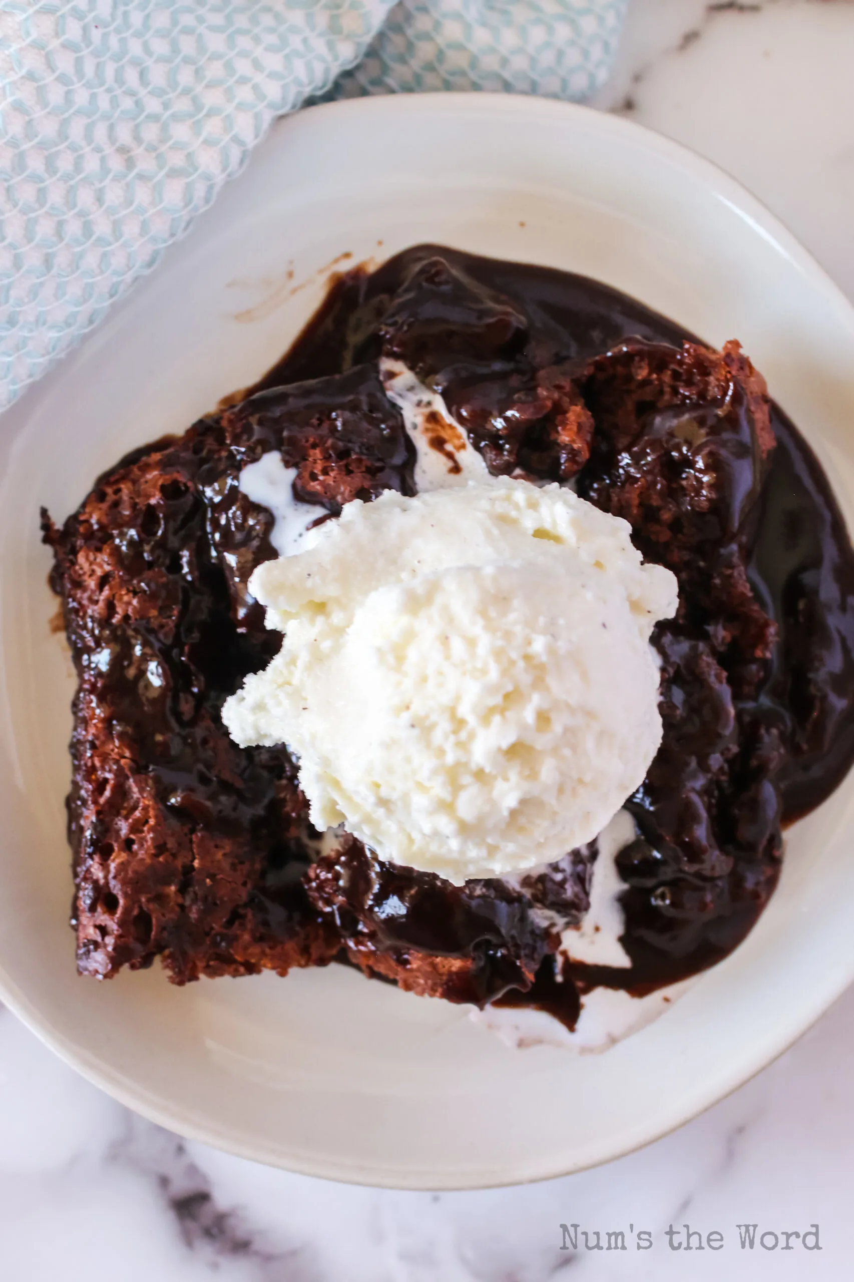 chocolate cobbler on a plate with a scoop of ice cream on top. Photo taken from the top looking down.