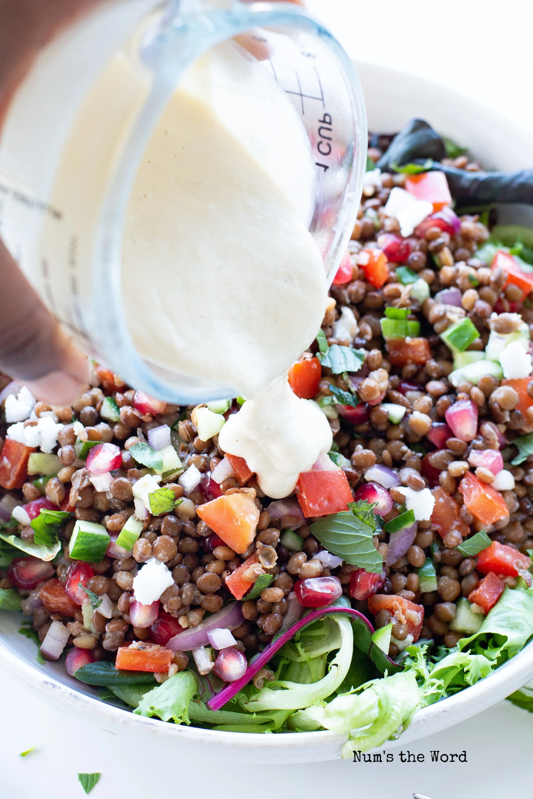 salad dressing being poured over lentil salad