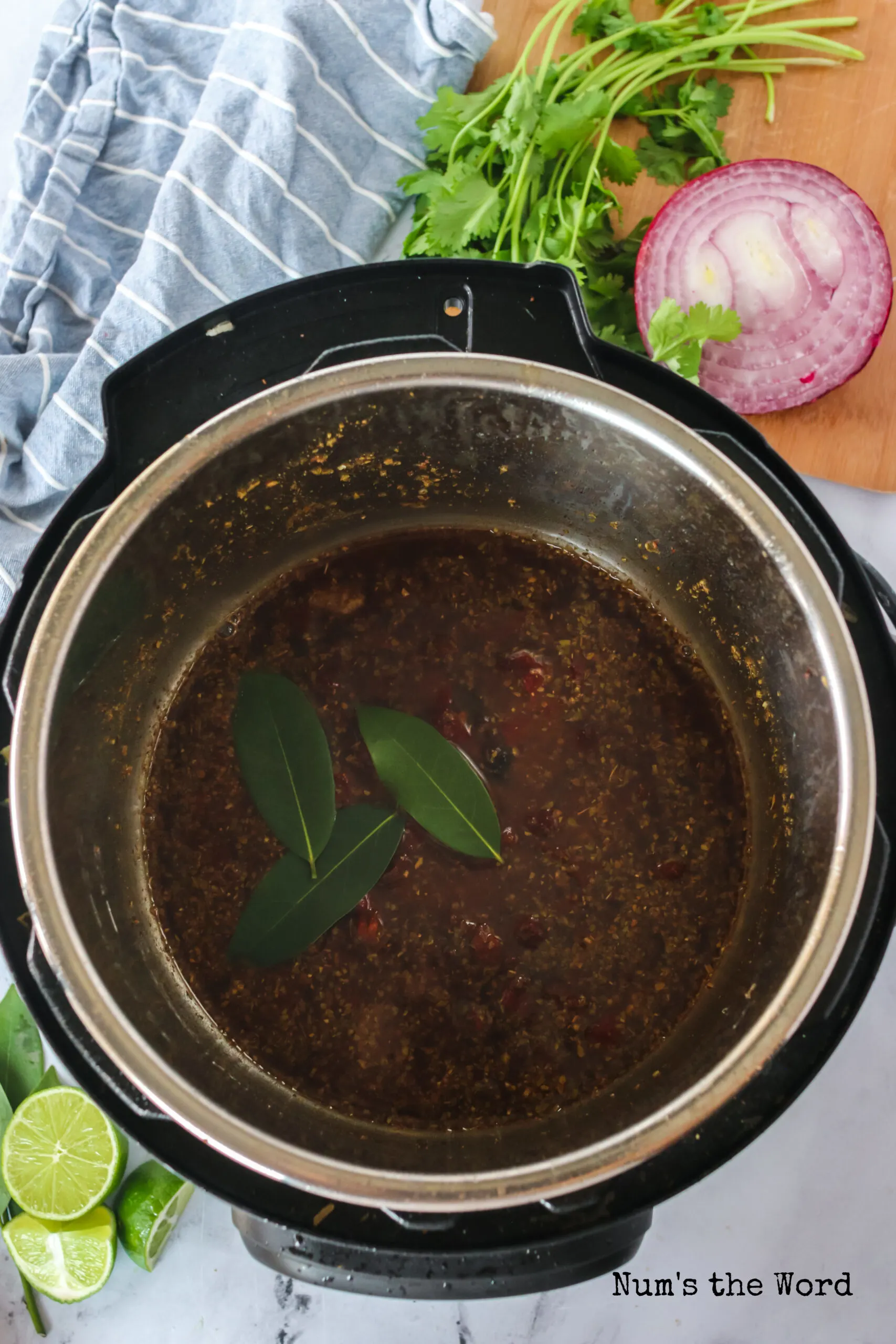 Beef broth mixture poured into empty instant pot with bay leaves.