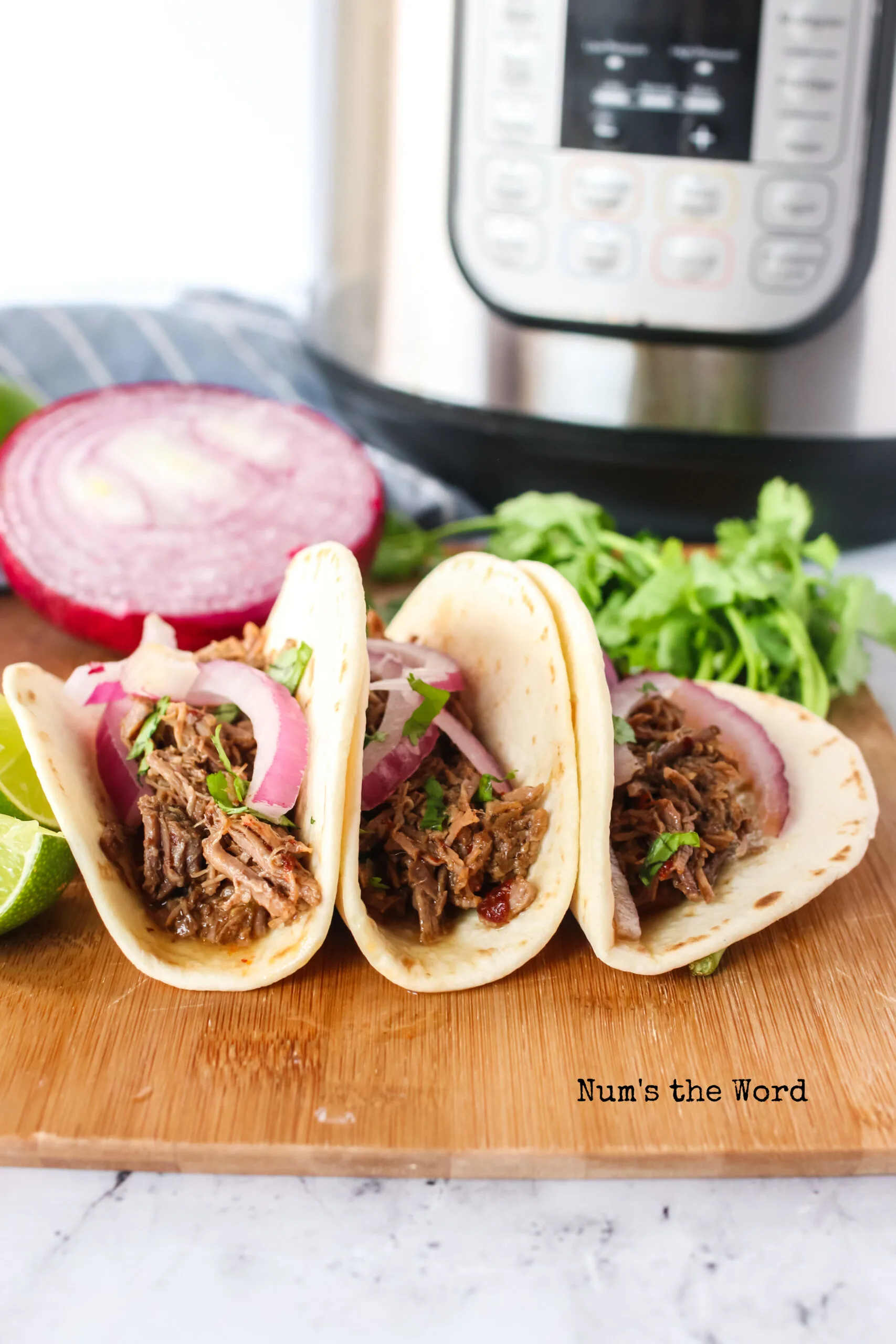 zoomed out image of 3 tacos with instant pot in the background