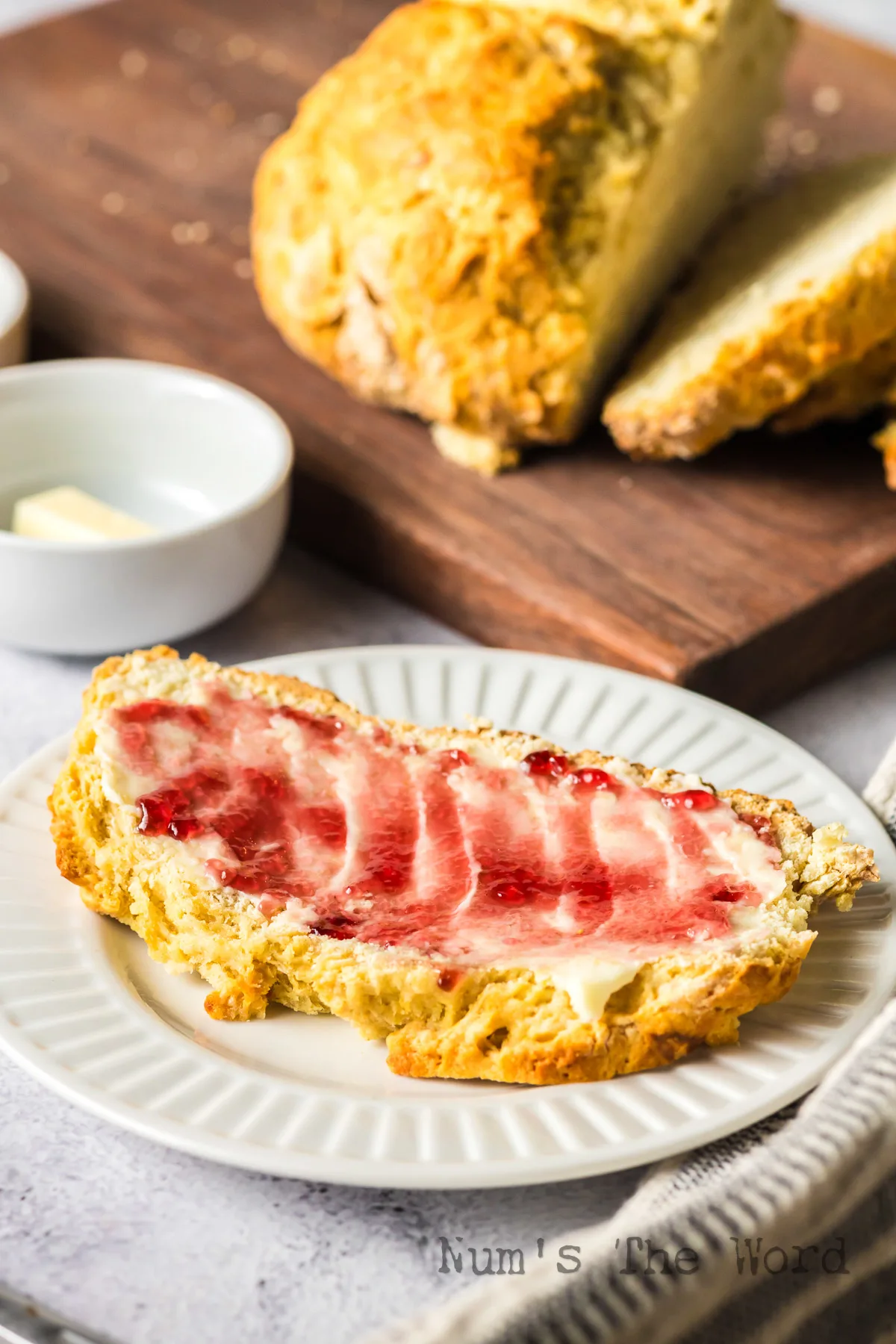 A slice of bread on a plate with butter and jam.
