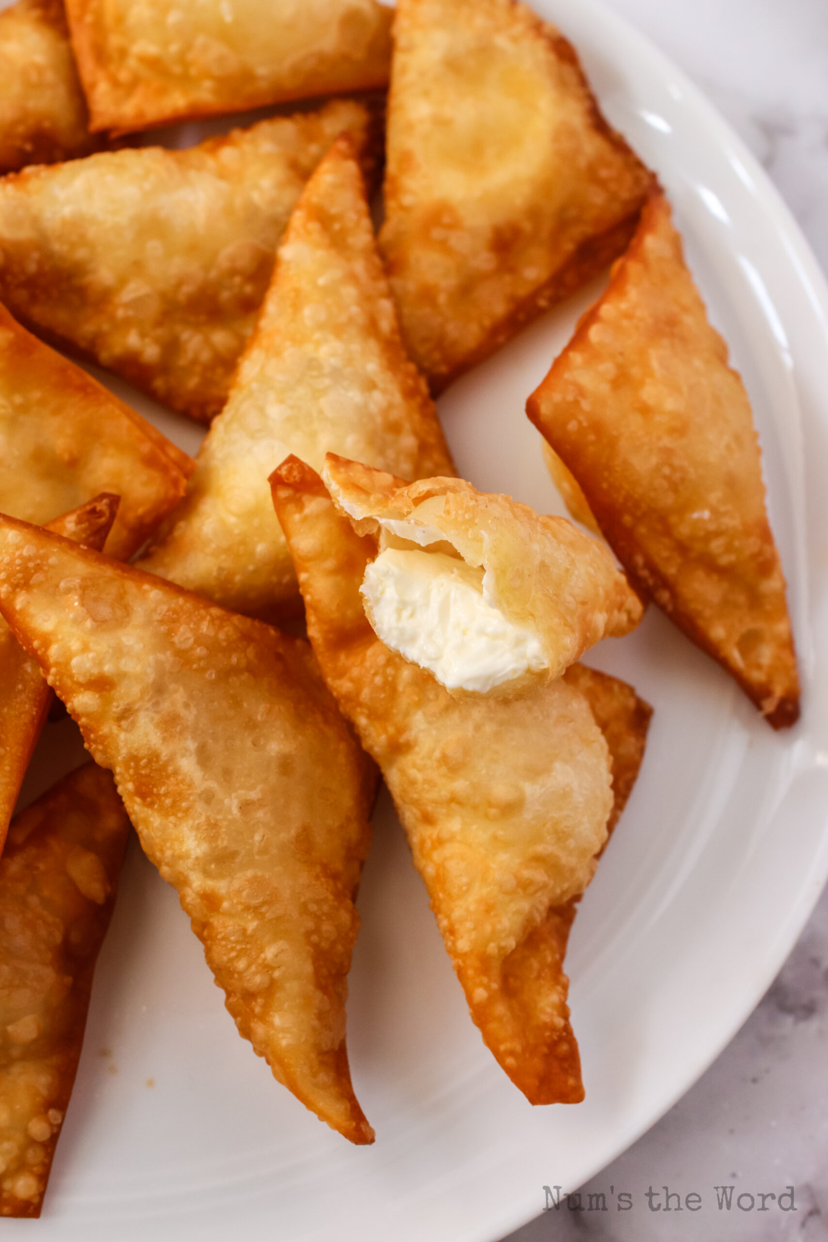 plate of wontons with one cut in half to show filling.