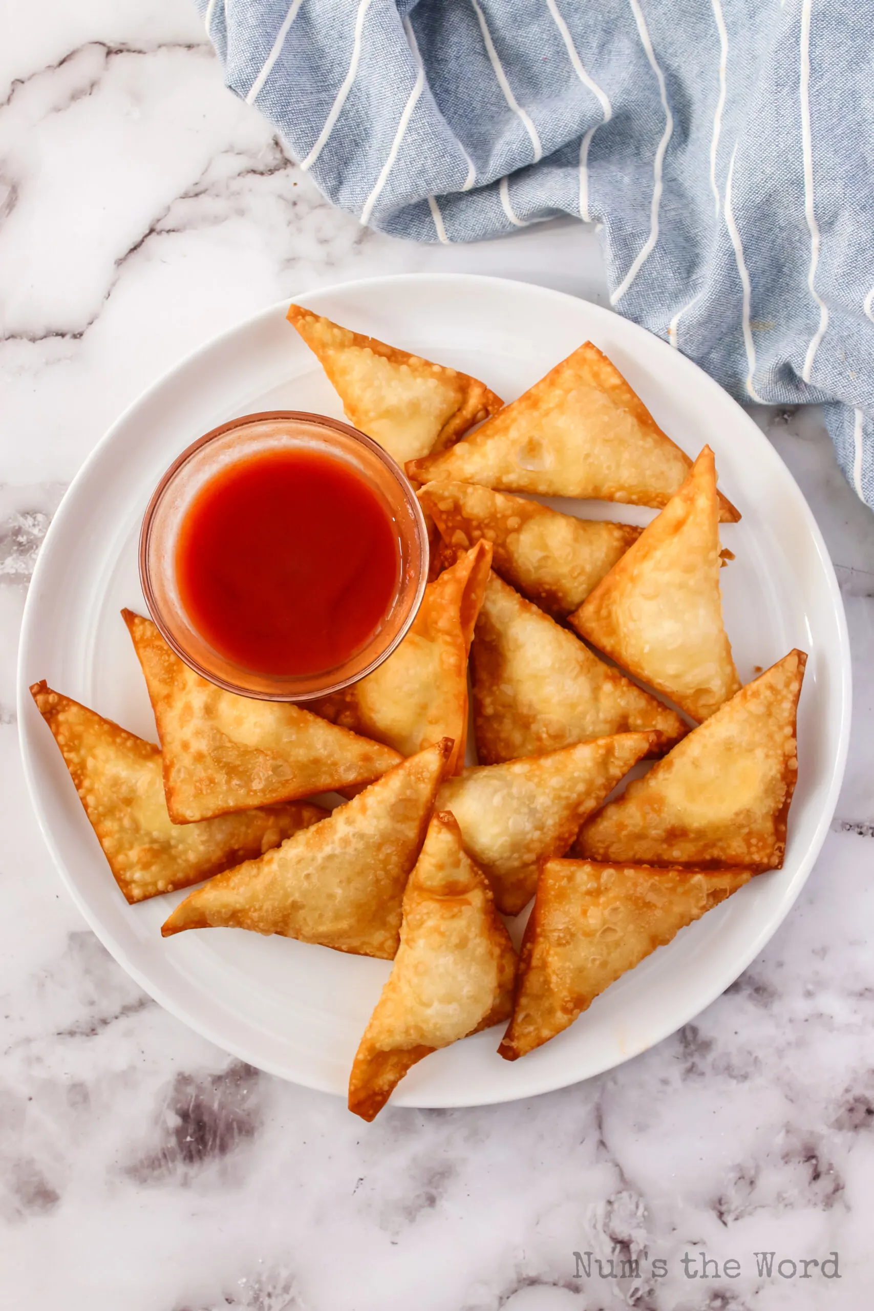 hot cream cheese wontons on a platter with a bowl of sweet and sour sauce