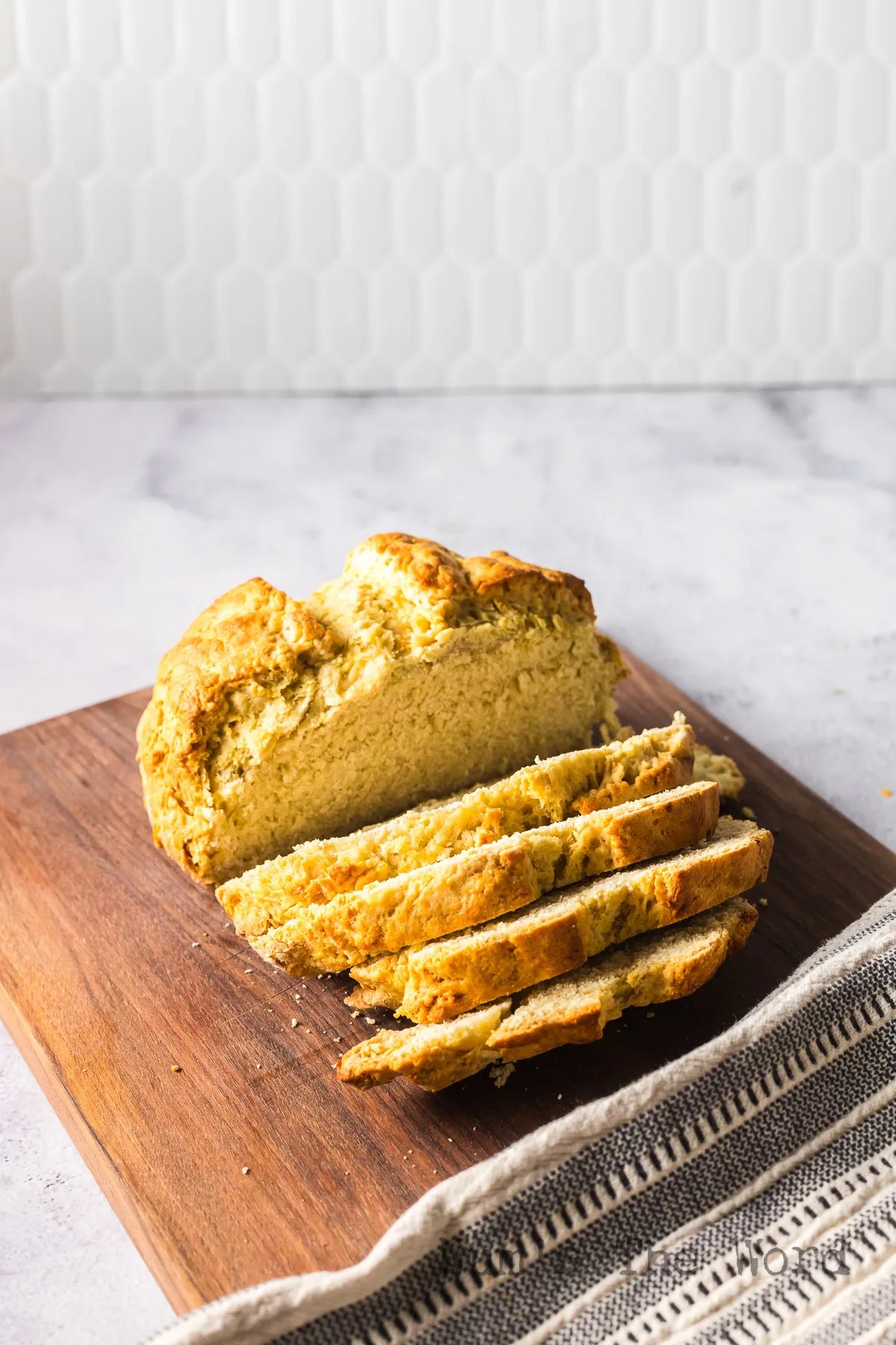 zoomed out image of bread on cutting board with several slices cut.