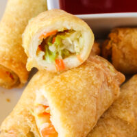 zoomed in image of egg rolls on plate with one cut in half.